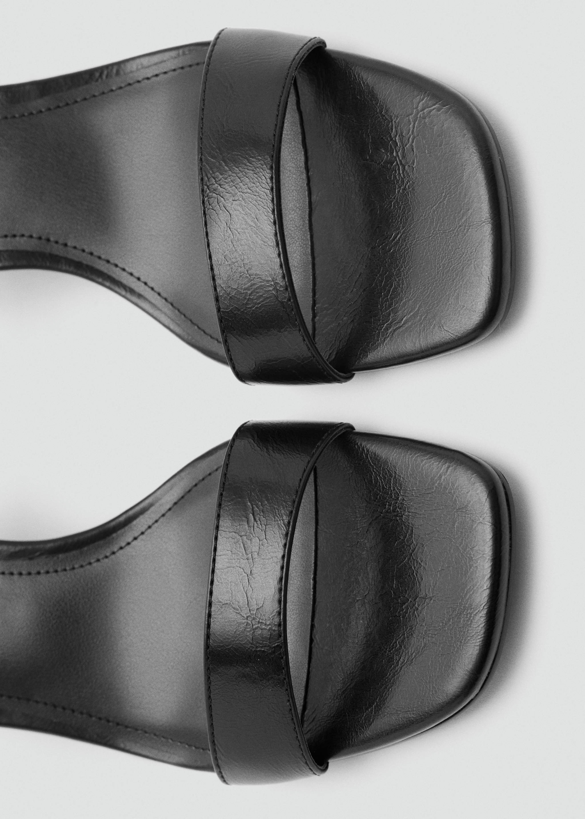 Close-up of black square-toe sandals featuring a single forefoot strap.