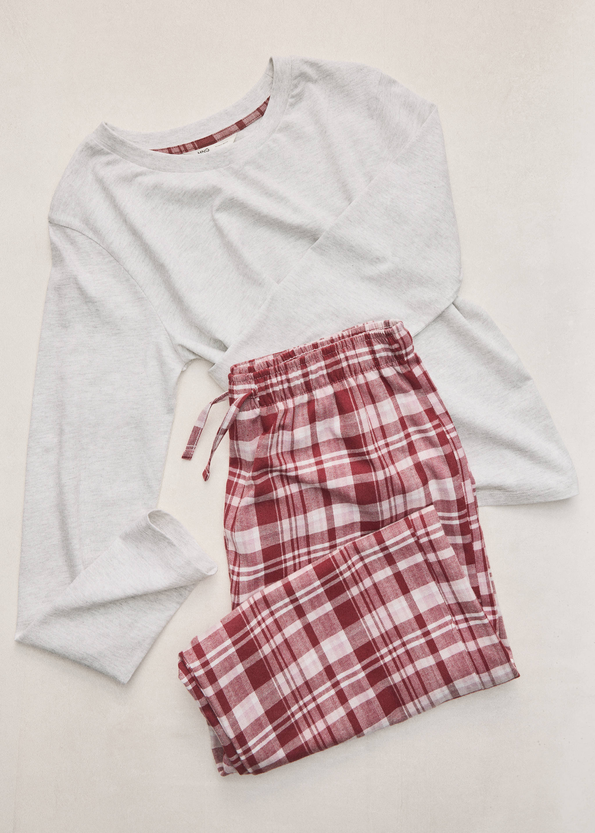Grey long-sleeved pyjama set with red plaid trousers.