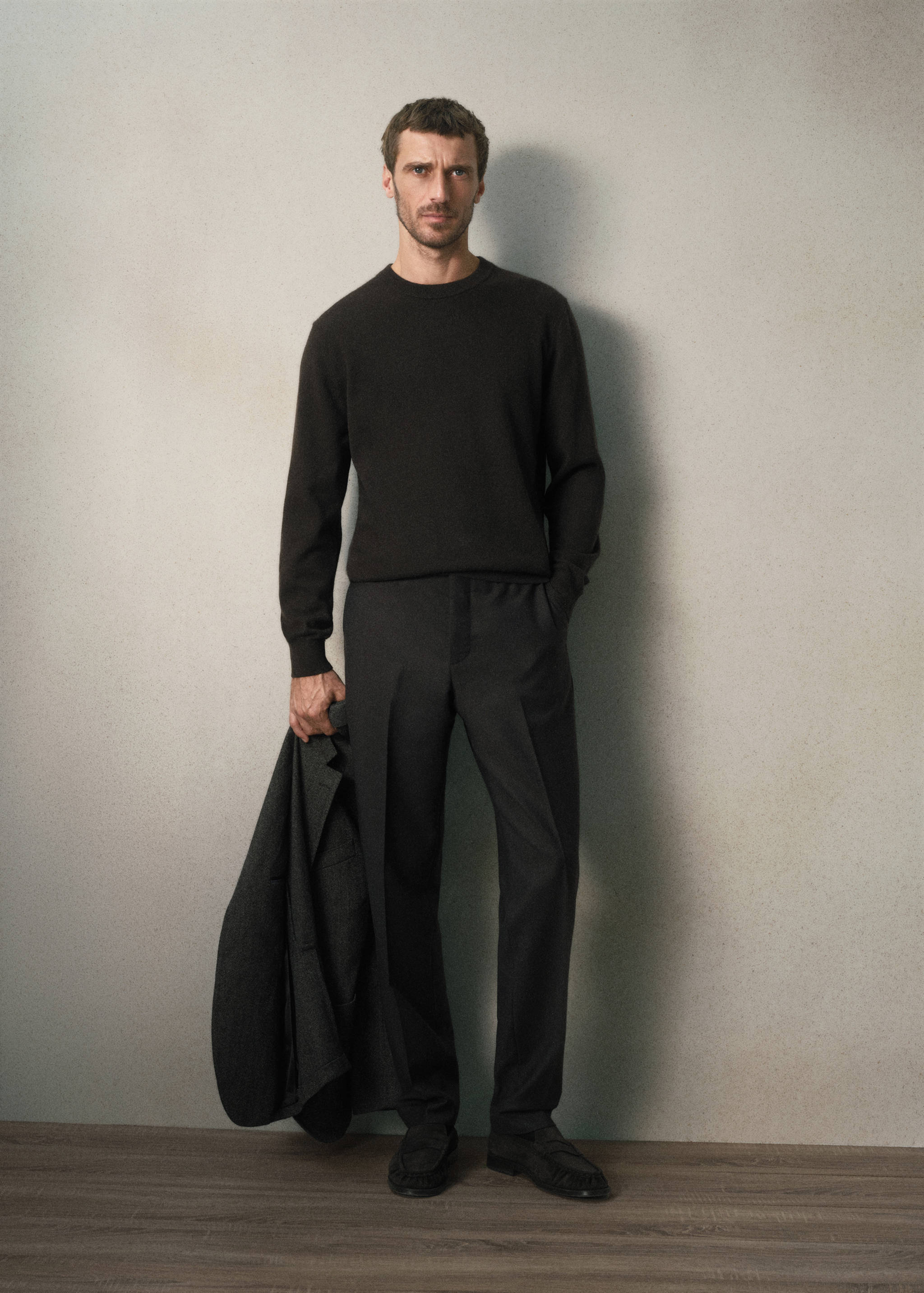 Dark grey trousers with a pressed crease, worn with a dark sweater and loafers.