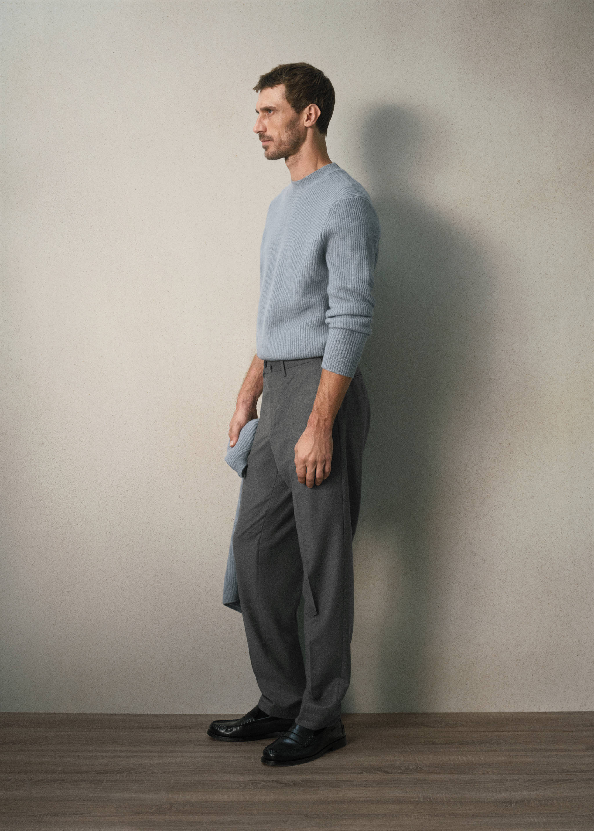 Dark grey trousers worn with a light blue ribbed sweater.