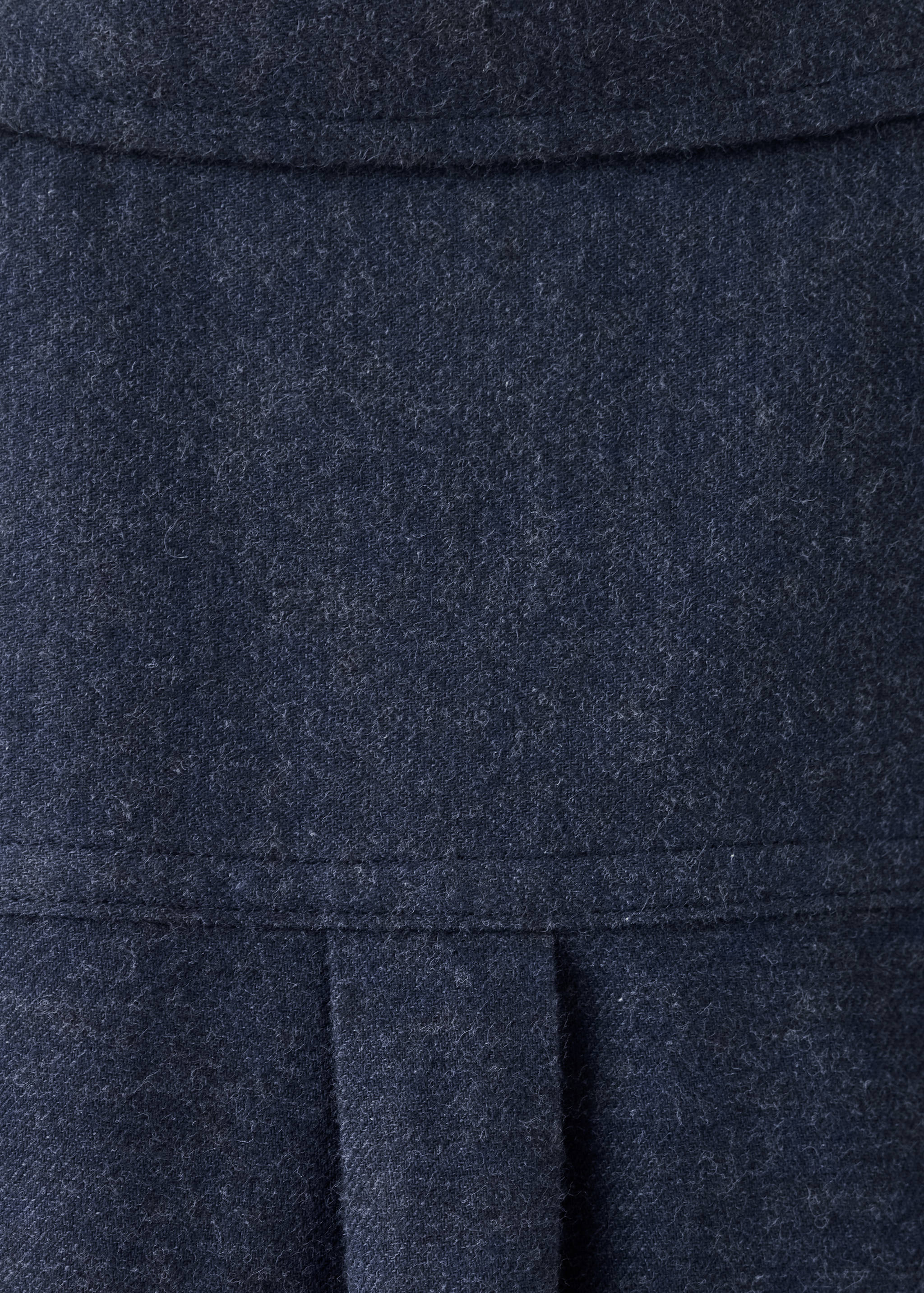 Close-up of dark grey shirt fabric texture featuring stitching and a back pleat.
