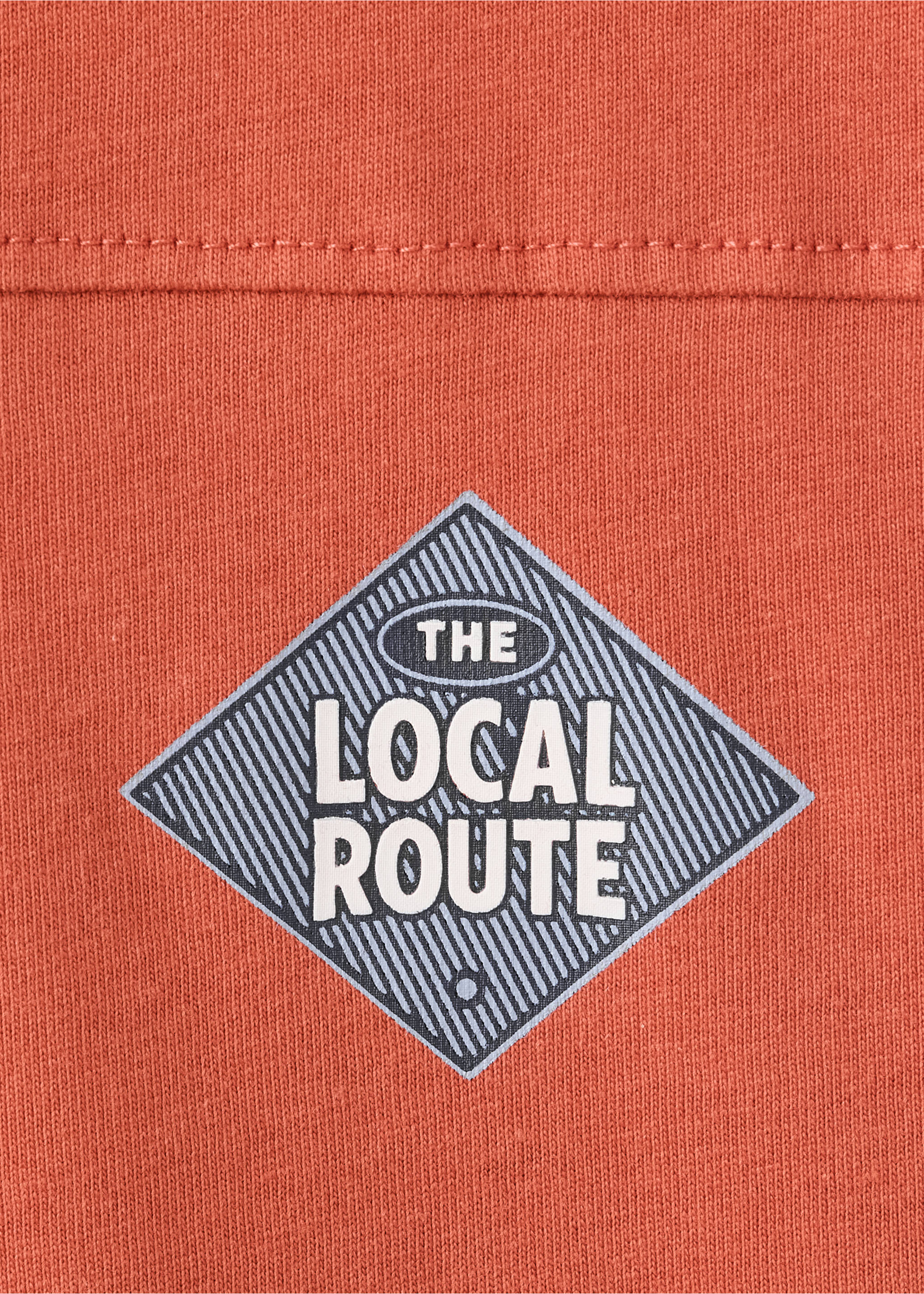Close-up of rust-orange T-shirt fabric with a graphic print., Russet. Ref: 37058632-00.