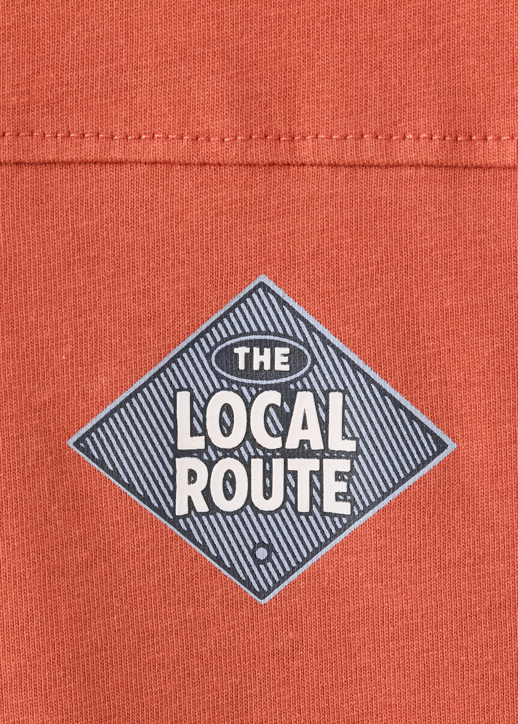 Close-up of rust-orange T-shirt fabric with a graphic print.