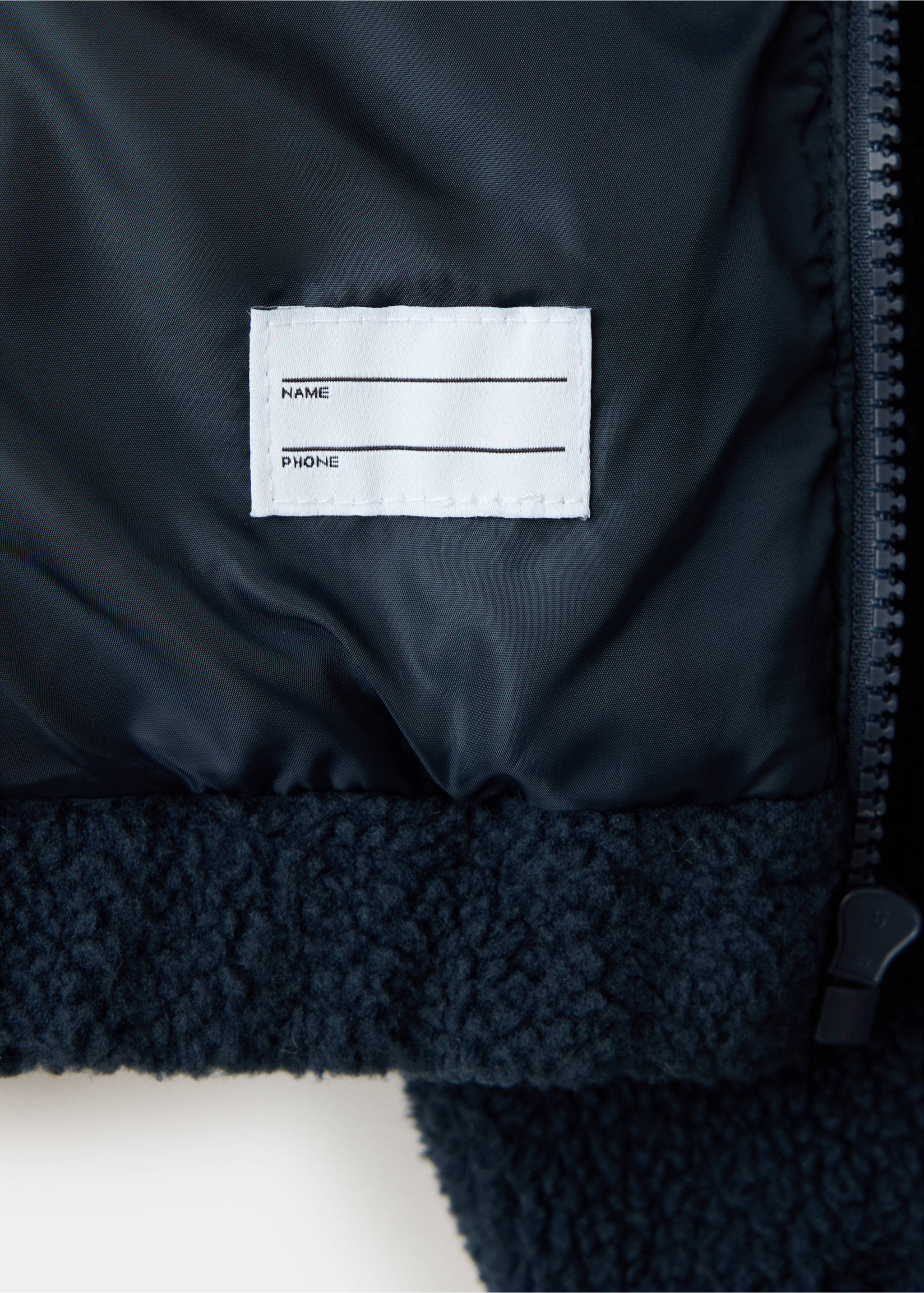 Close-up of a navy jacket interior showing fabric label and lining., Navy. Ref: 37058634-00.