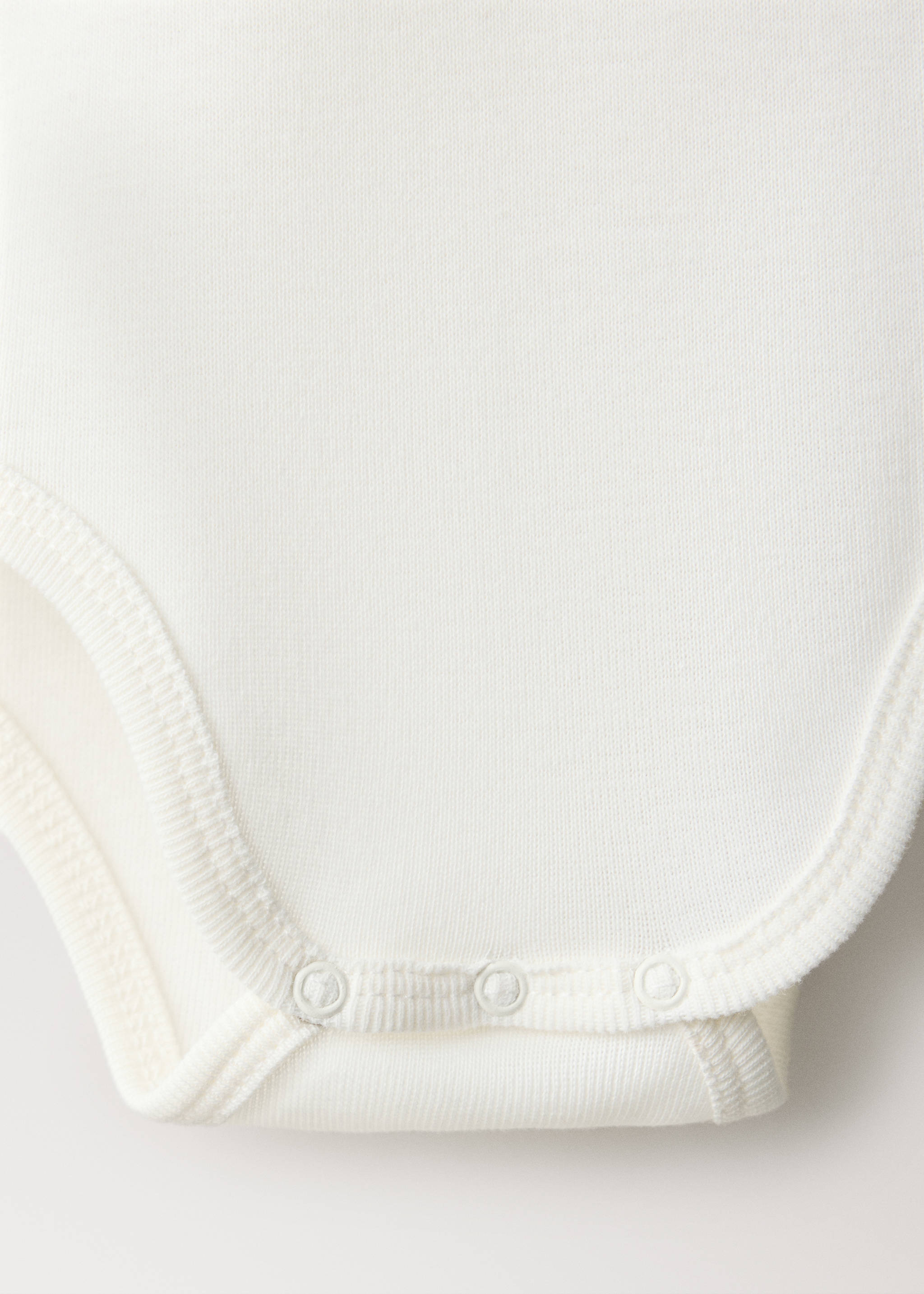 White baby body detail showing snap-fastener closure and ribbed trim.