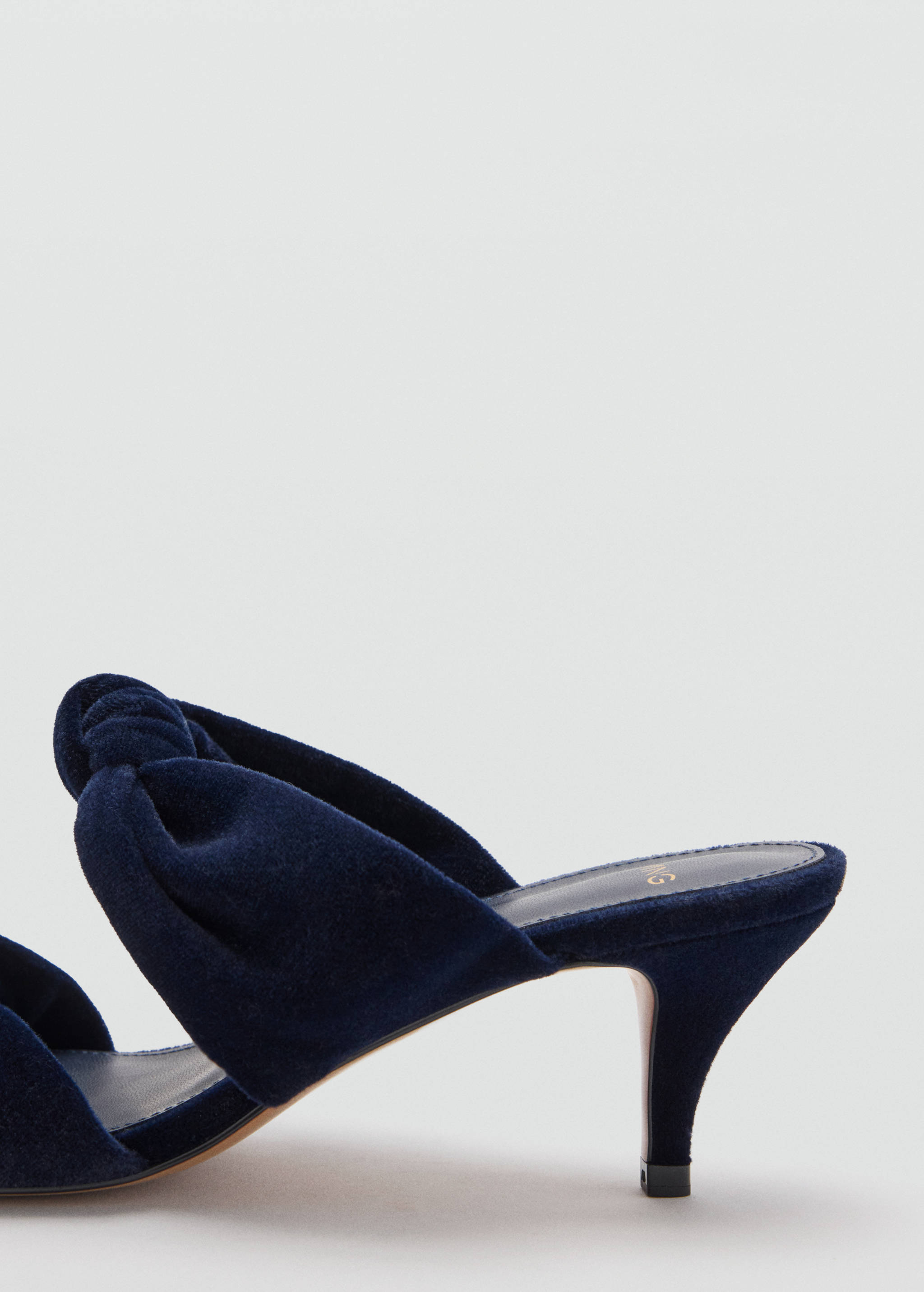 Dark blue heeled sandal with a knotted upper strap and kitten heel in close-up.