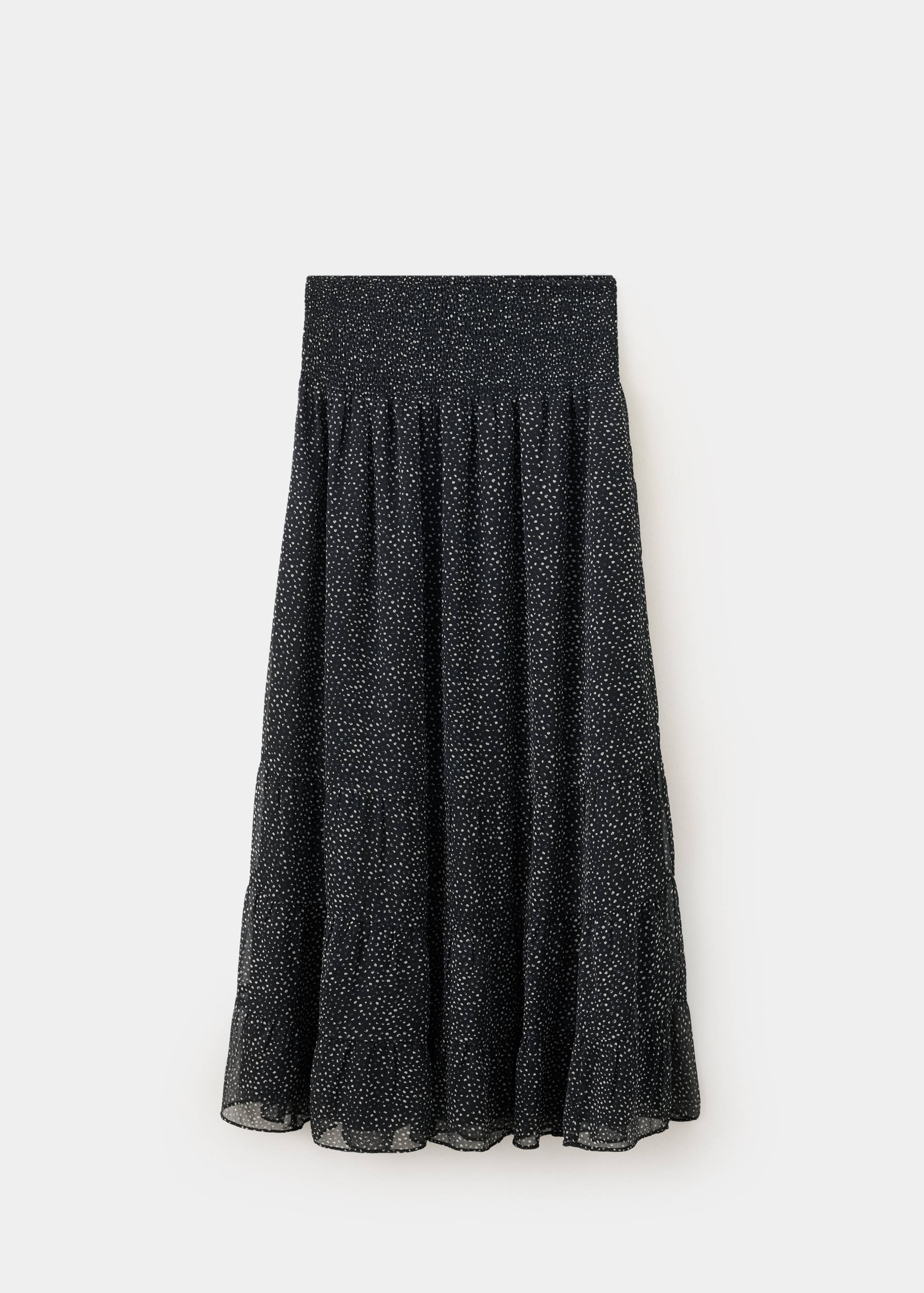 Falda negra de volantes con cintura tipo nido de abeja y estampado de pequeños lunares blancos.