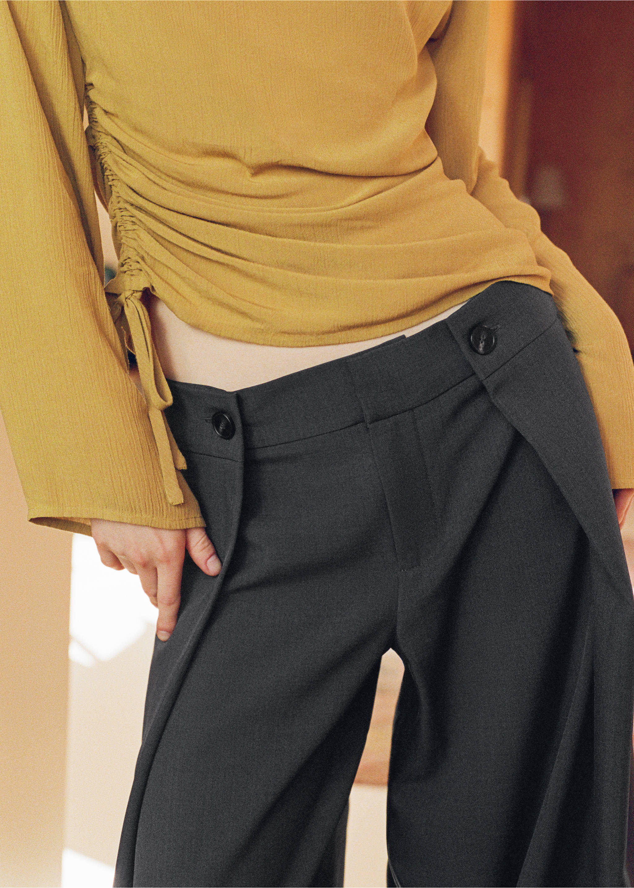 Dark grey trousers with a buttoned overlay waistband detail, worn with a mustard yellow top., Grey. Ref: 37059117-00.