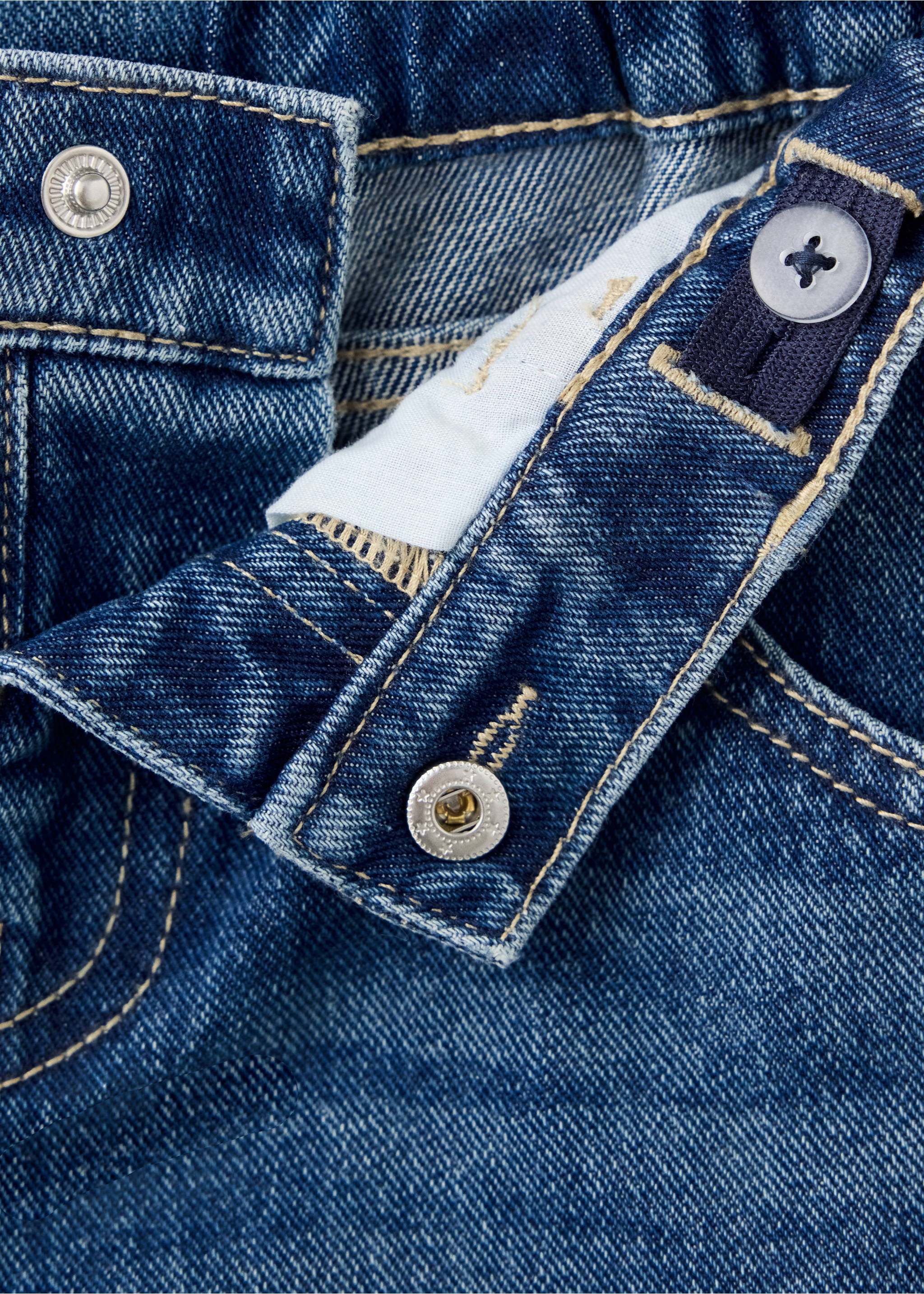 Close-up of blue denim trousers waistband with adjustable detail., Dark Blue. Ref: 37059121-00.