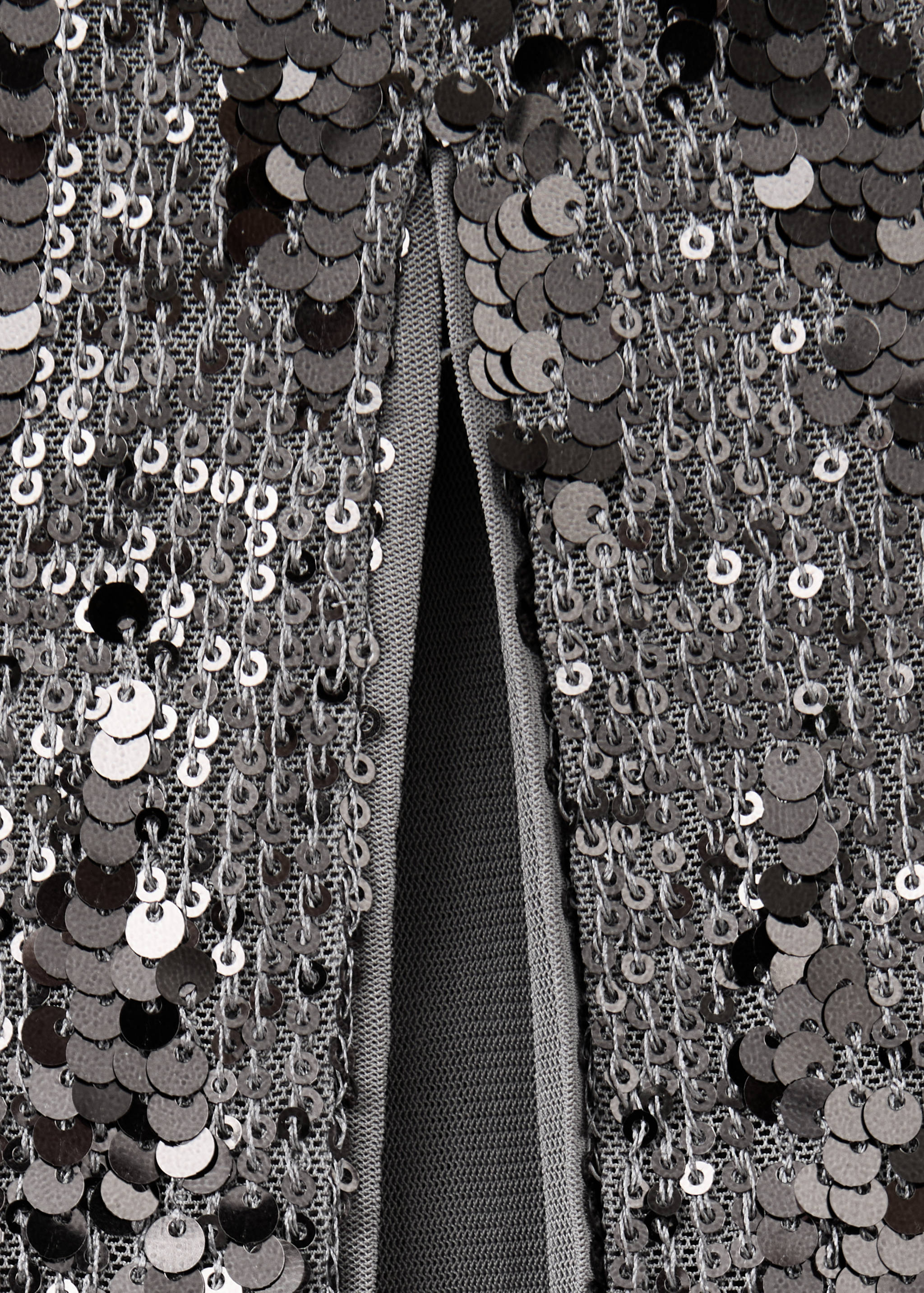 Close-up of a dark grey sequinned skirt detail with a slit.