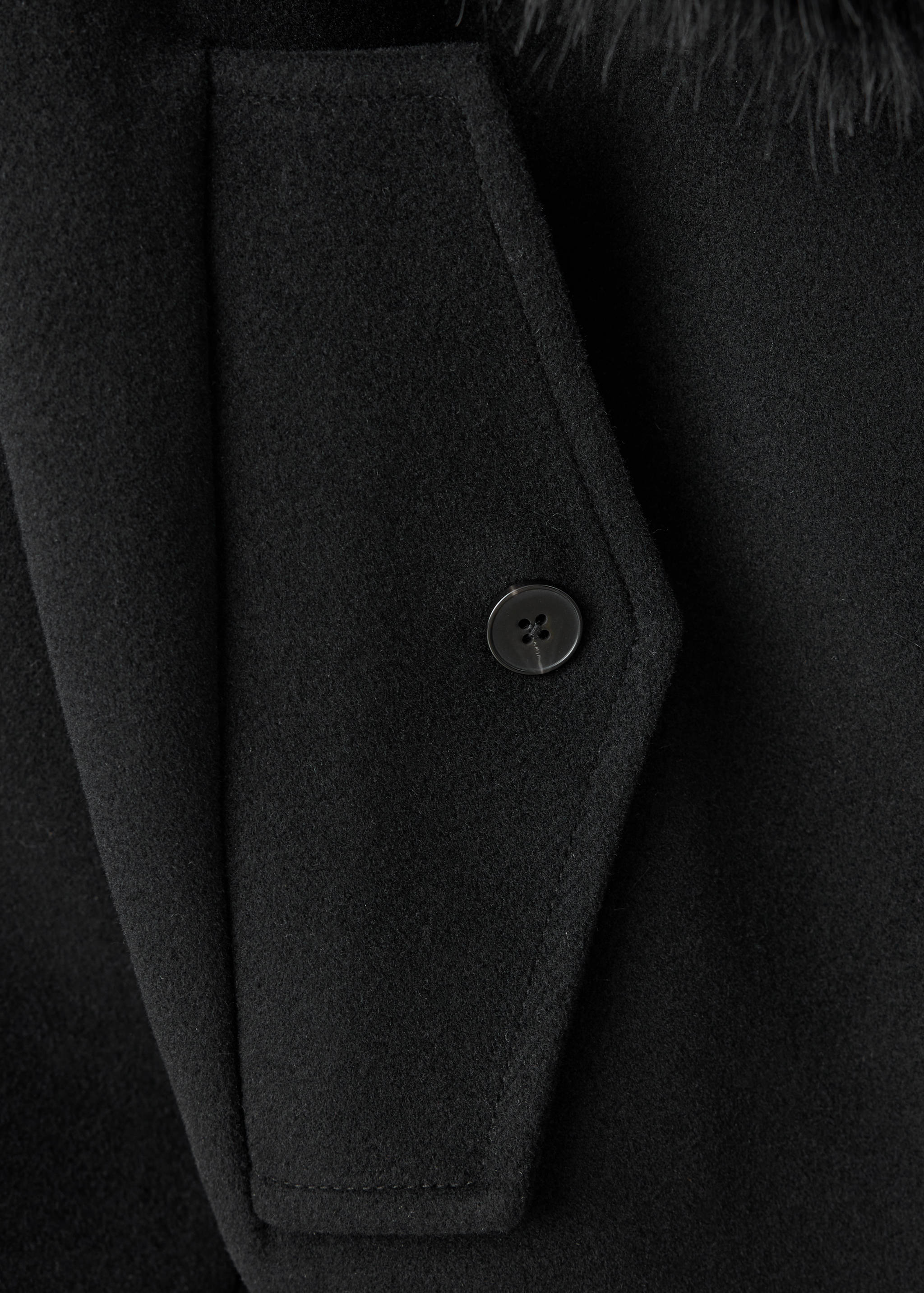 Black jacket pocket detail with button closure.
