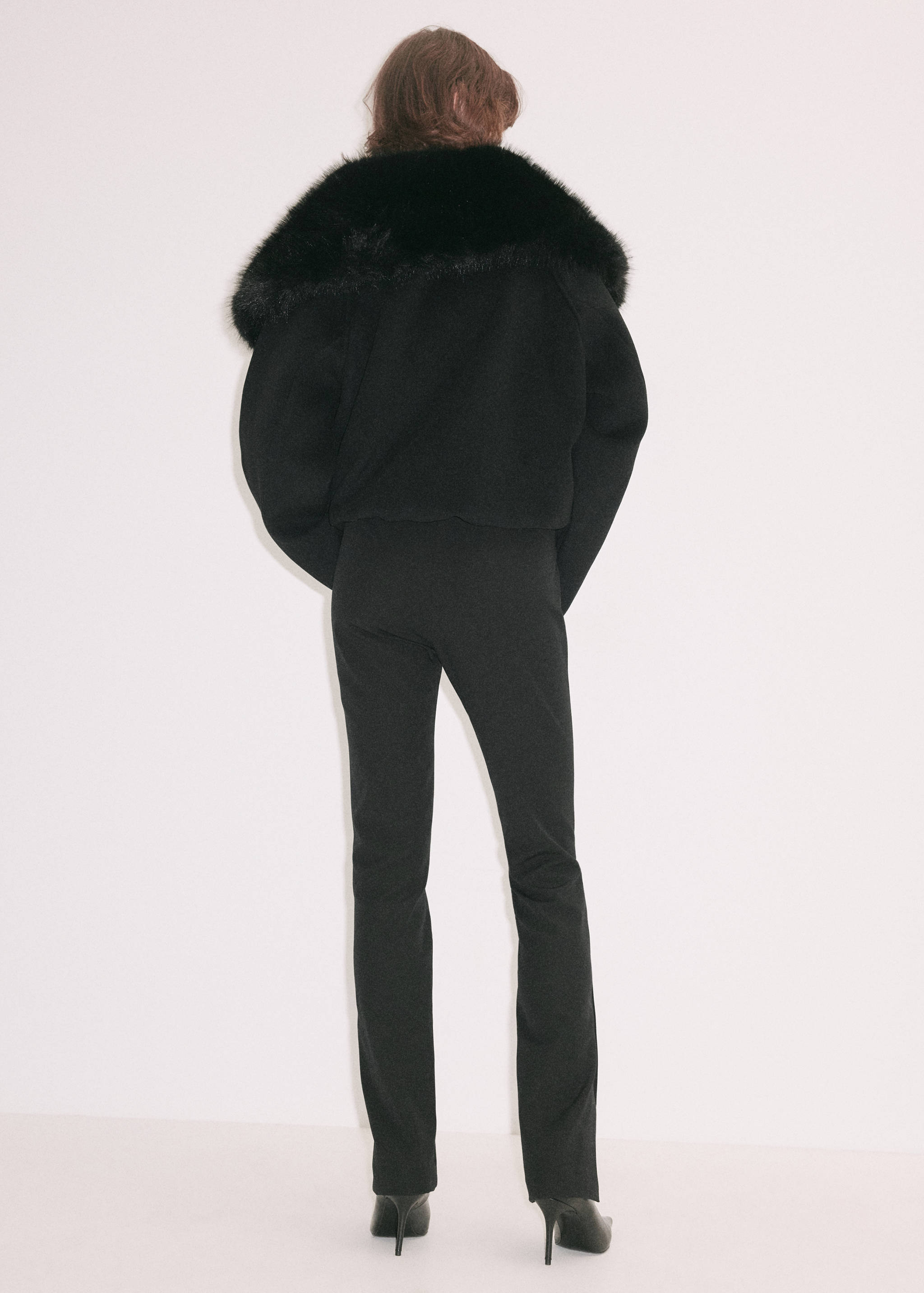 Vista trasera de unos pantalones negros combinados con una chaqueta negra.