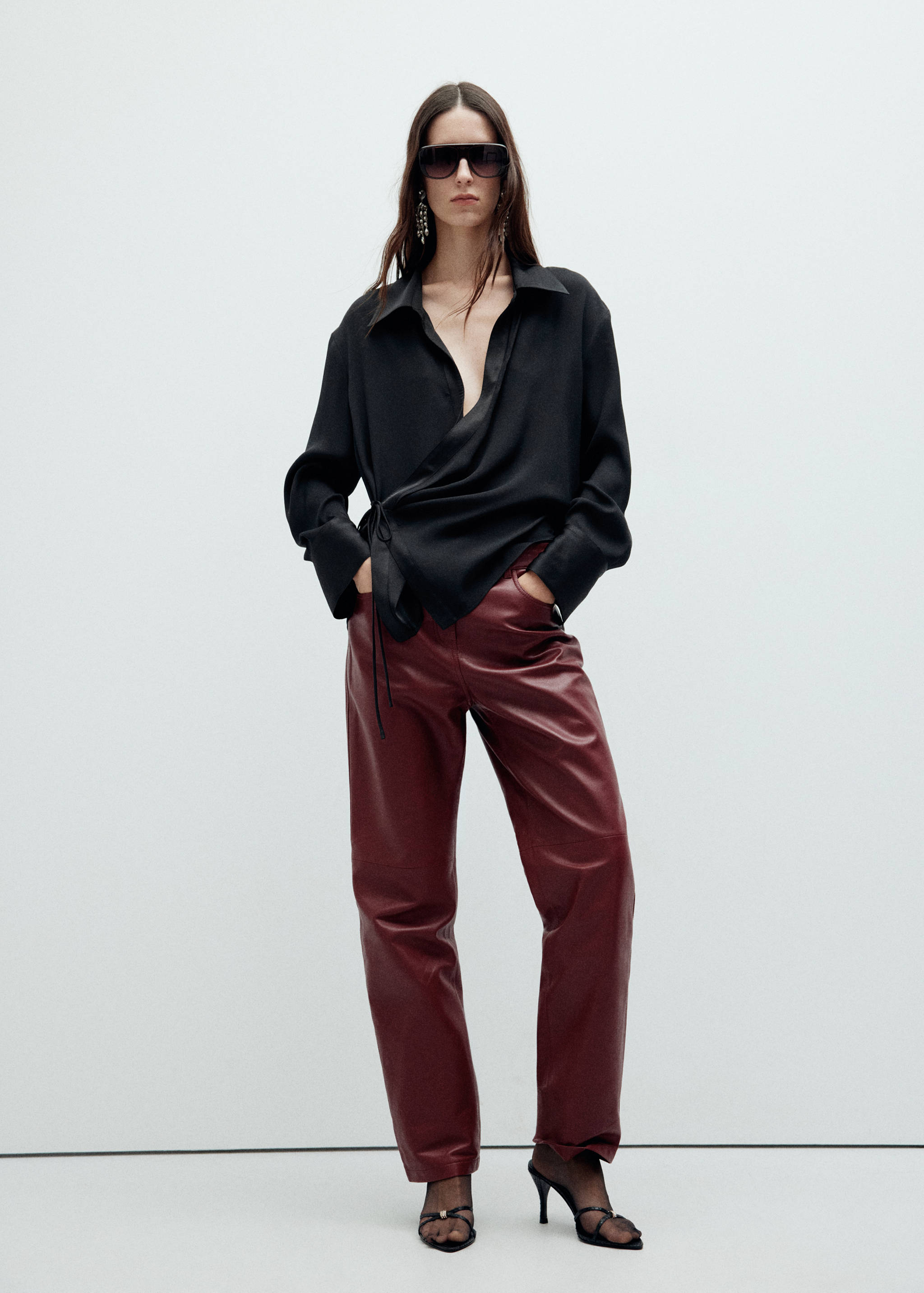 Black wrap shirt with collar and side ties, styled with burgundy trousers.