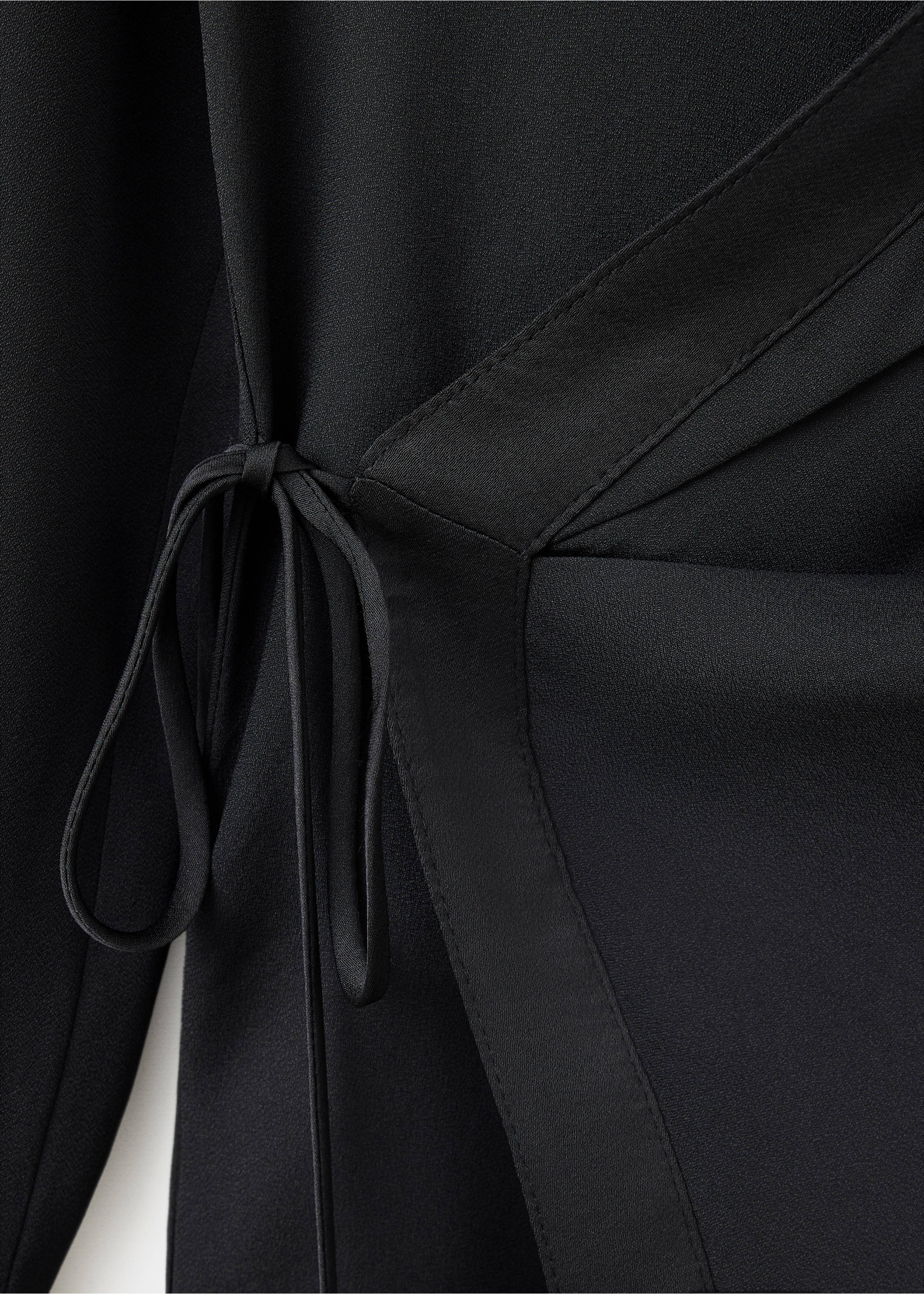 Close-up of a black shirt featuring a wrap design with side tie fastenings., Black. Ref: 37059129-00.