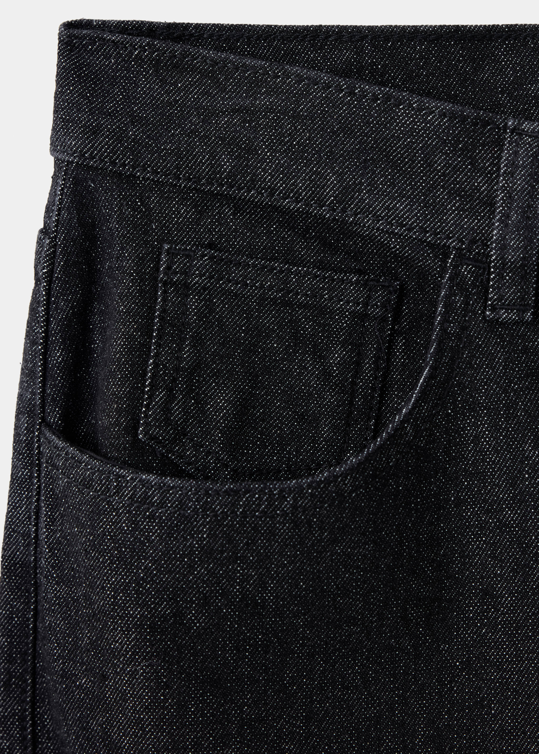 Primer plano de pantalones tejanos de denim gris oscuro que se centra en el tejido y el detalle del bolsillo.