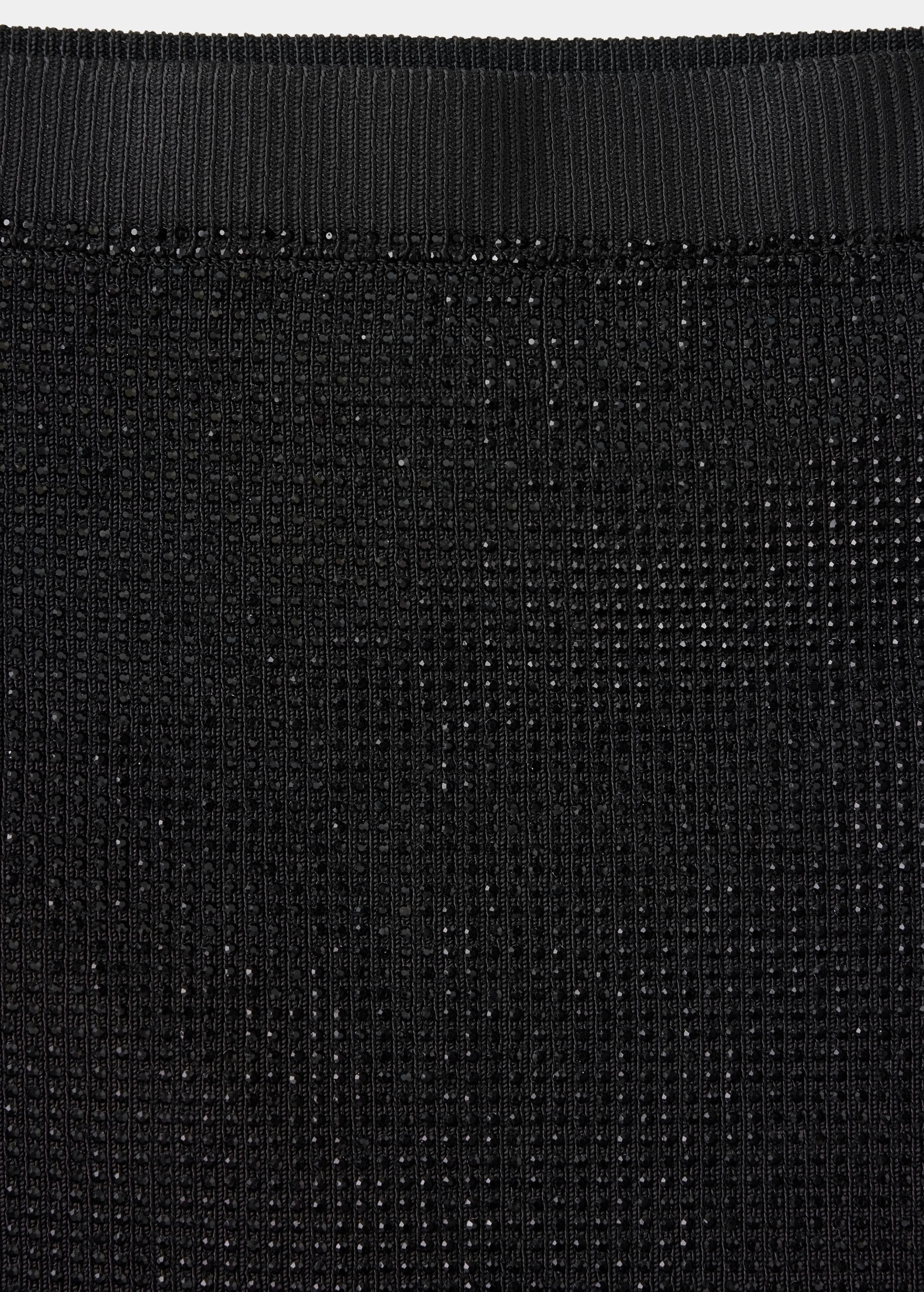 Close-up of a black embellished knit skirt with a ribbed waistband.