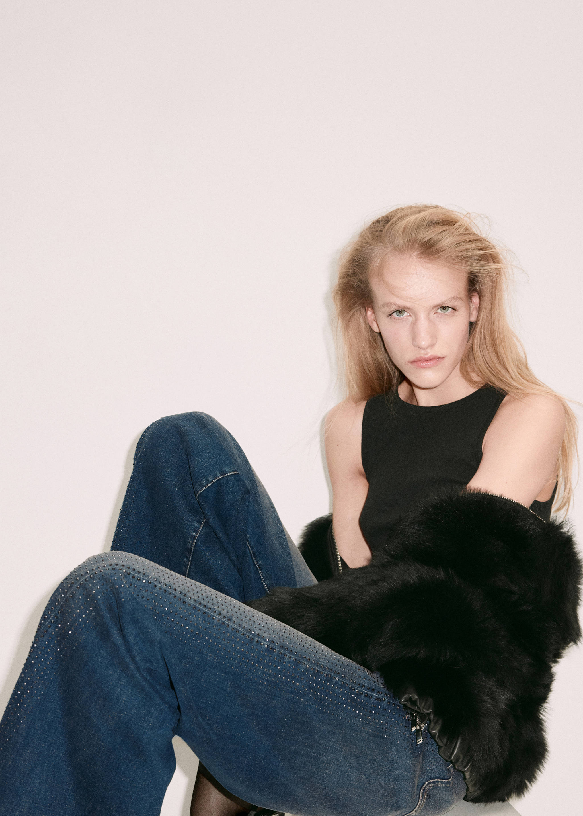 Primer plano de modelo con pantalones vaqueros azul oscuro con pedrería de cristal y top negro.