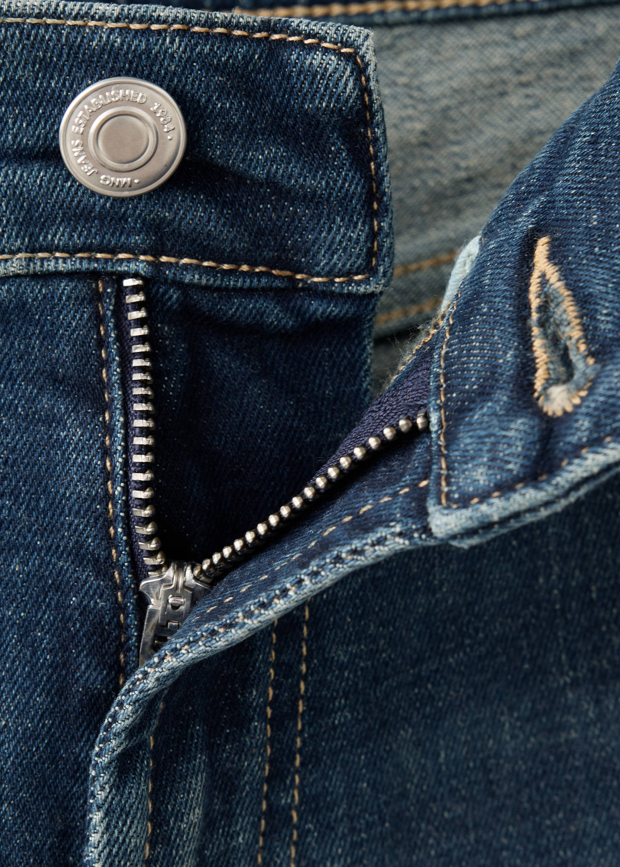 Close-up of blue denim jeans waistband and zip fly.