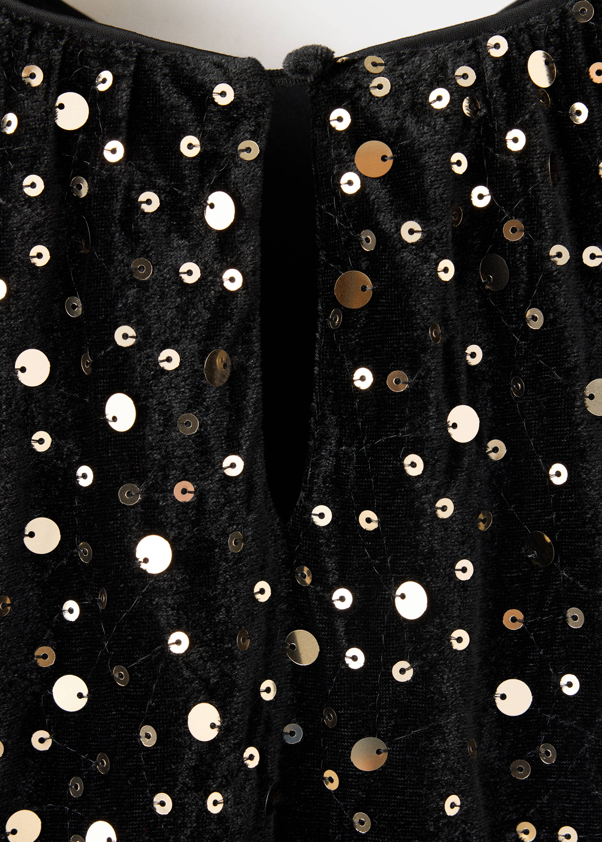 Close-up of a black sequinned kids dress showing the fabric texture and keyhole neckline.