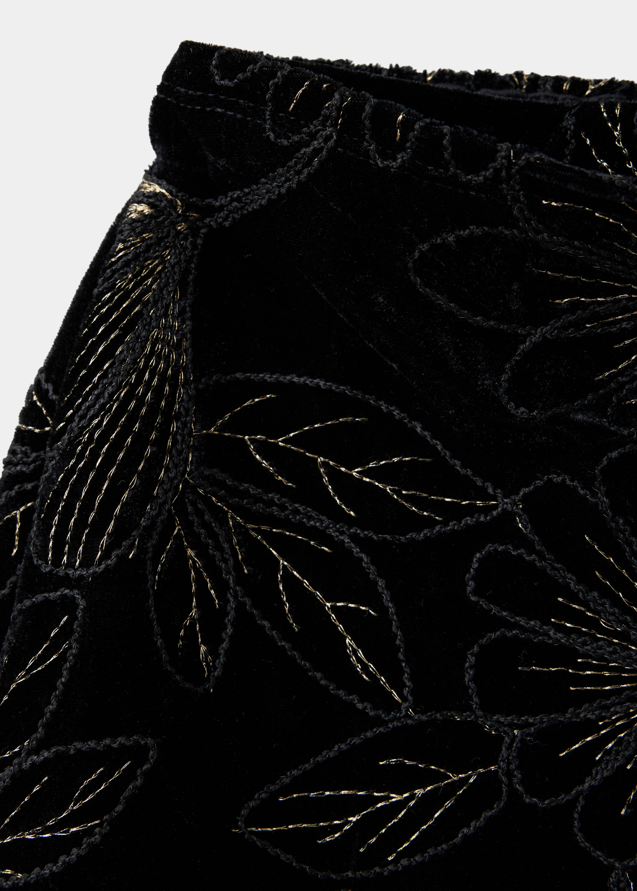 Close-up of black velvet shorts with gold embroidered floral details.