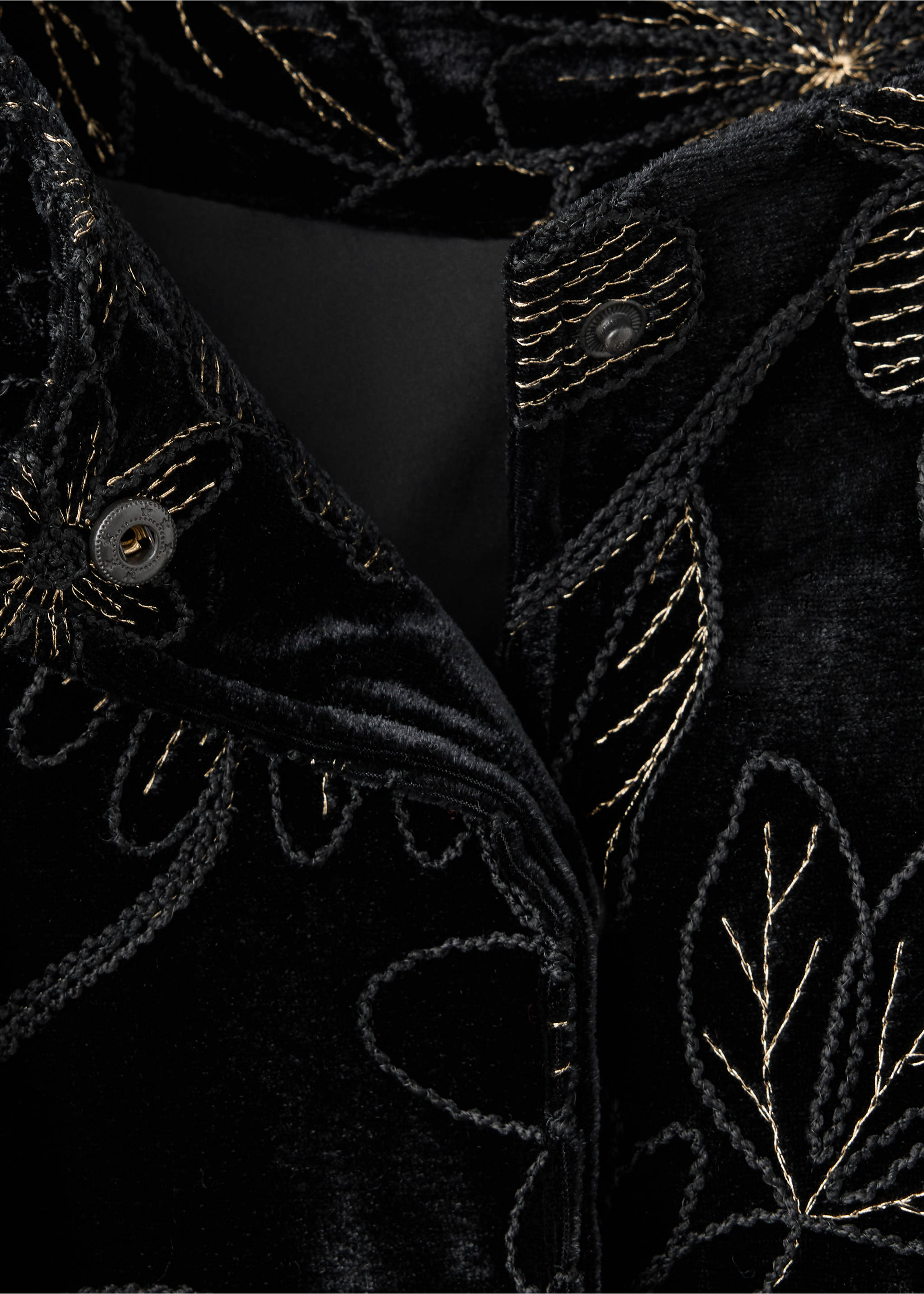 Close-up of a black velvet jacket with metallic gold embroidery and snap buttons., Black. Ref: 37059213-00.