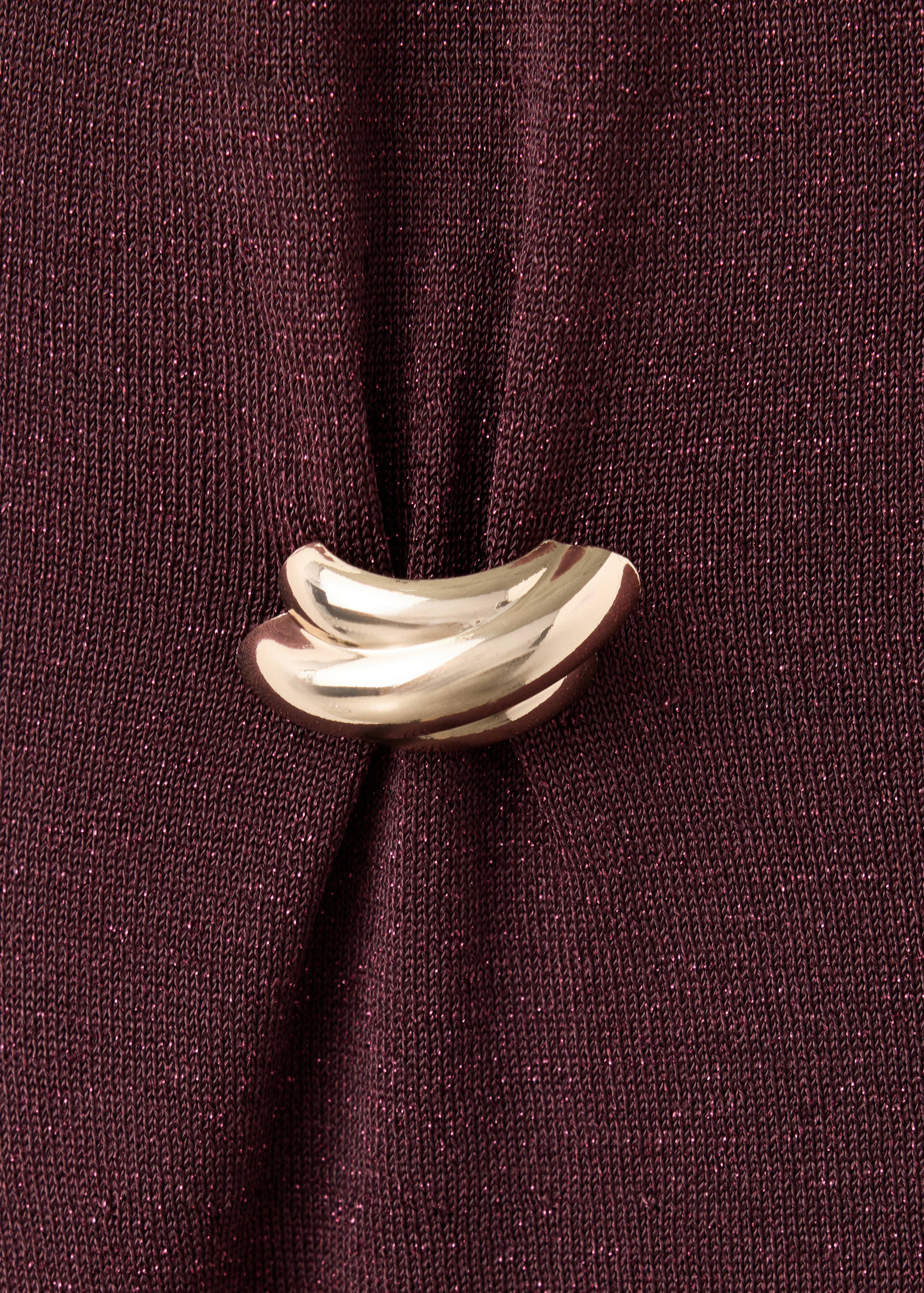 Burgundy metallic dress fabric detail featuring a polished gold-toned decorative clasp.