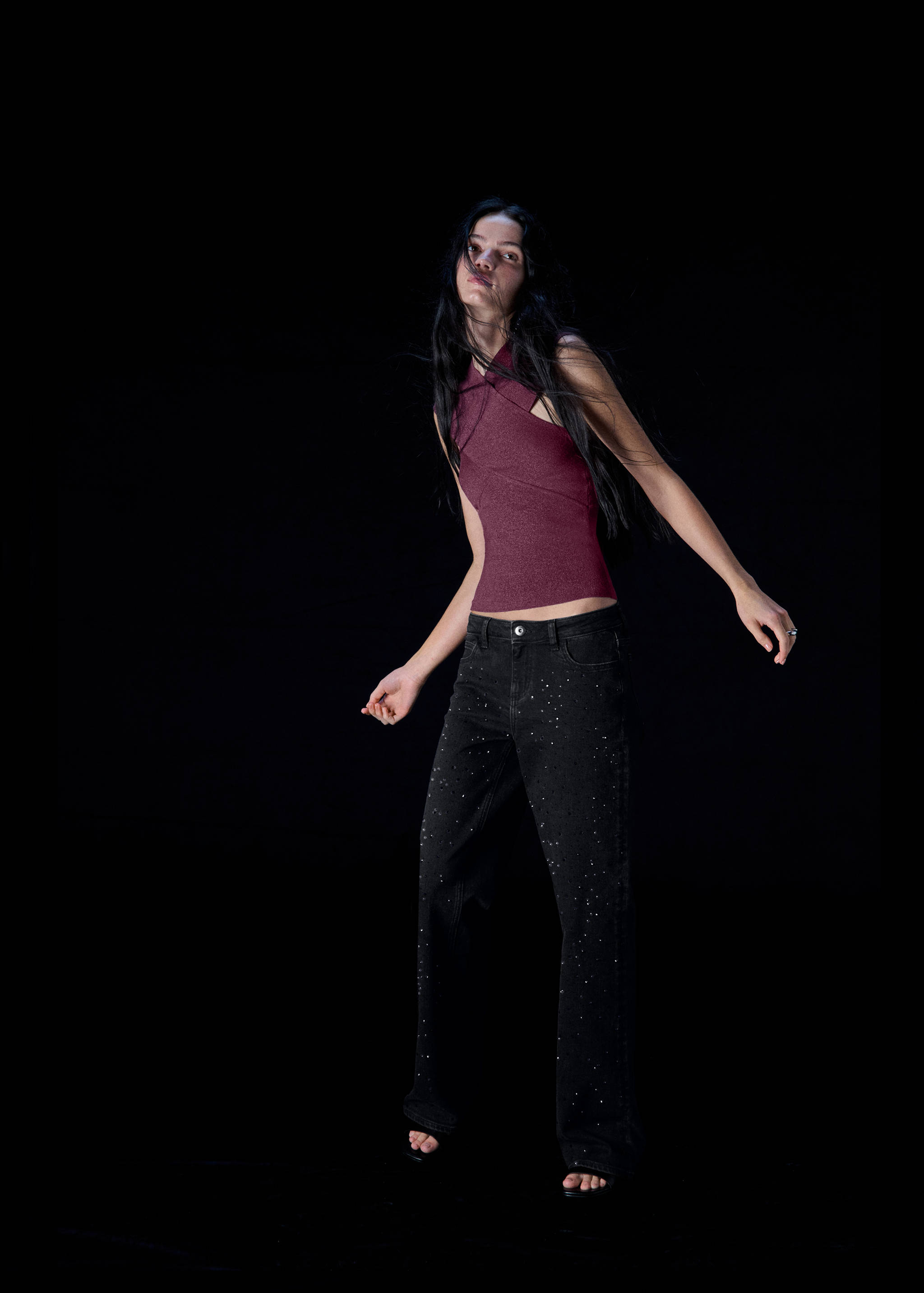 Black rhinestone-studded denim trousers worn with a burgundy halter top