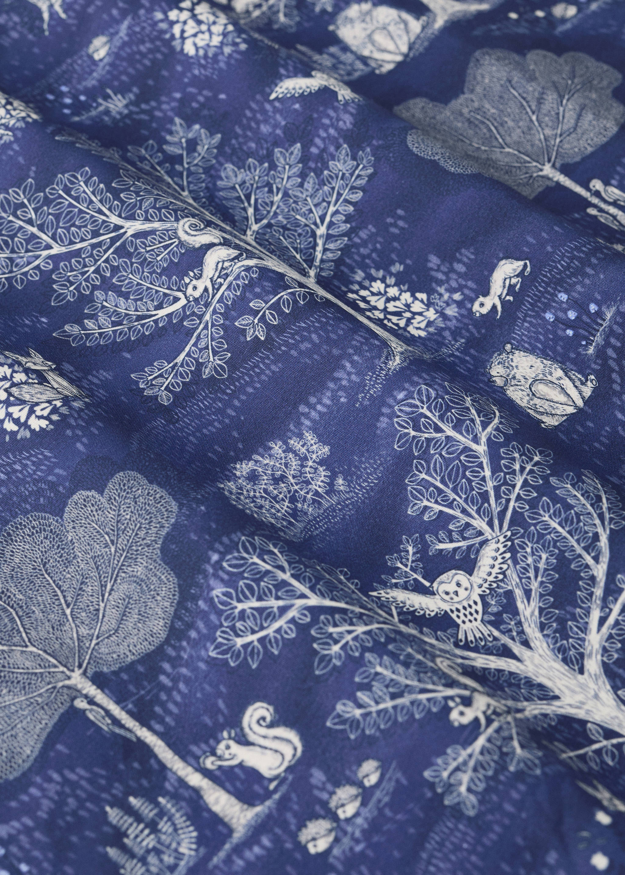 Blue cot duvet cover with a white woodland animal print detail
