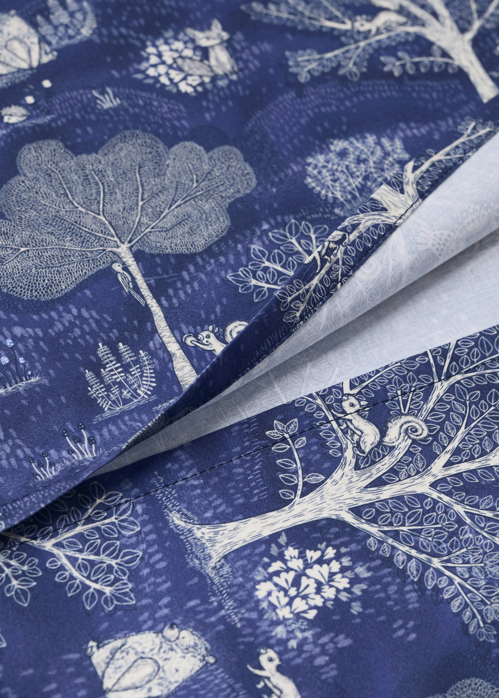 Blue cot duvet cover with a white illustrated woodland print.