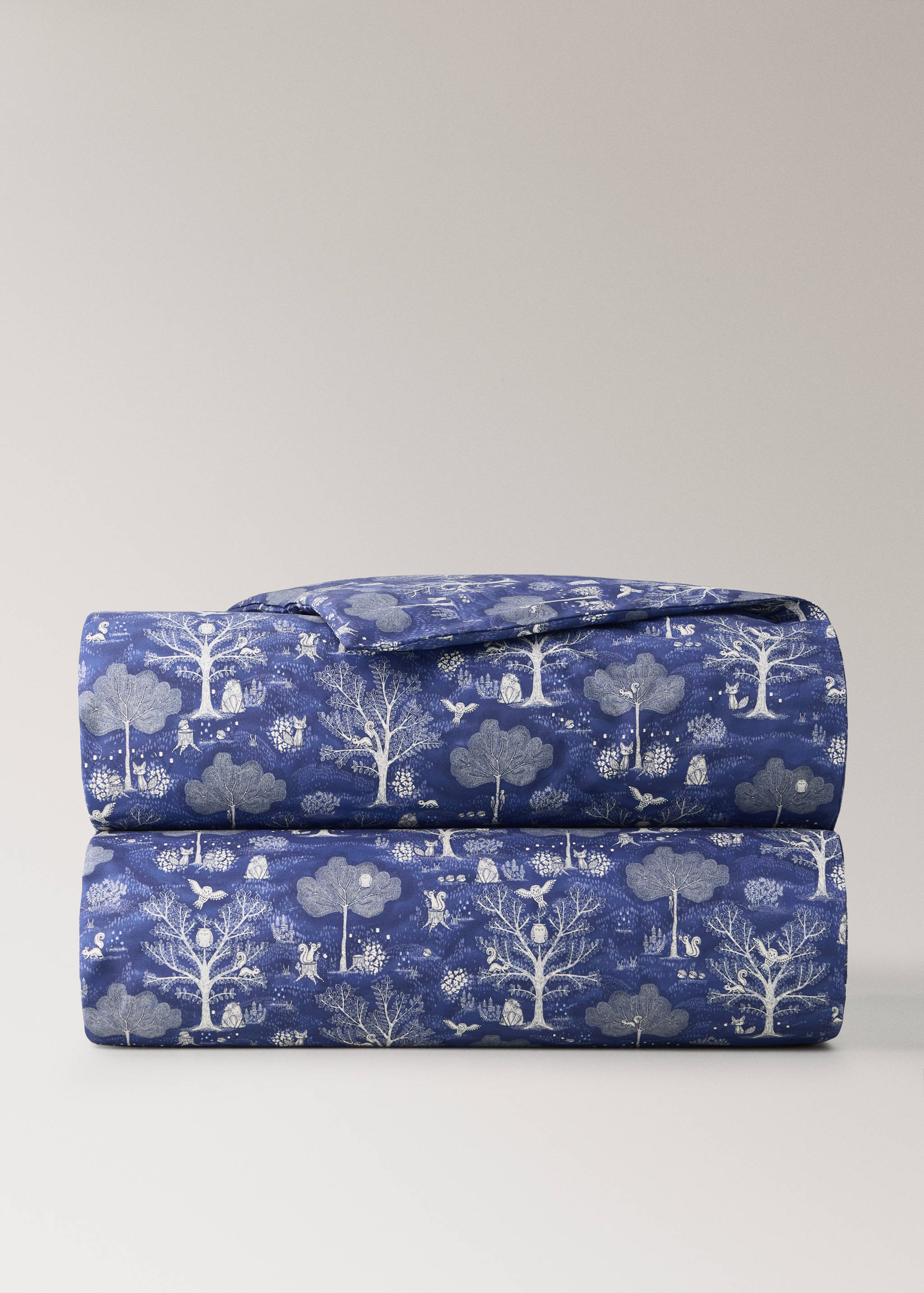 Blue woodland-print cot duvet cover featuring white trees and animals.
