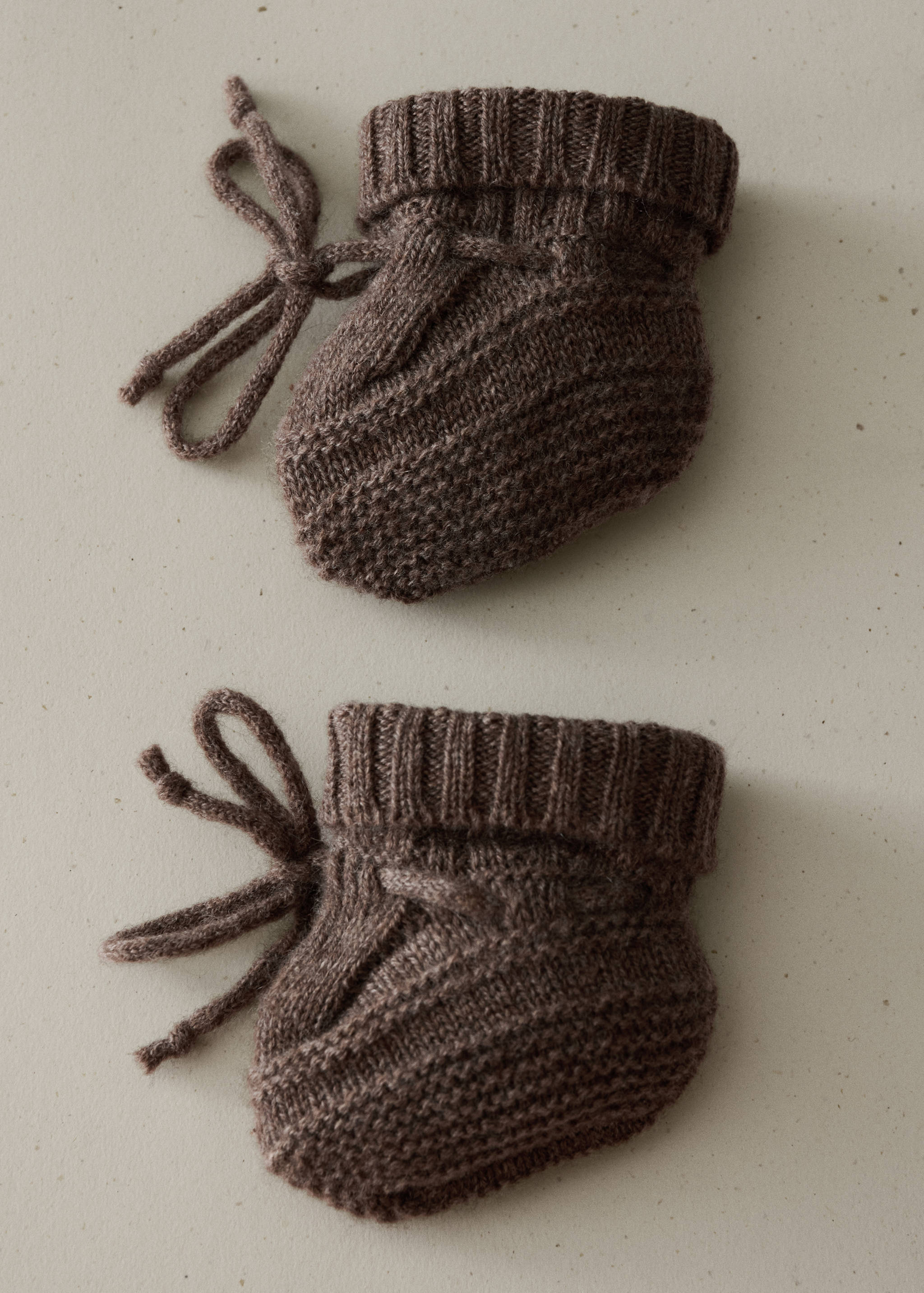 Brown knit baby socks with ribbed cuffs and side tie strings.