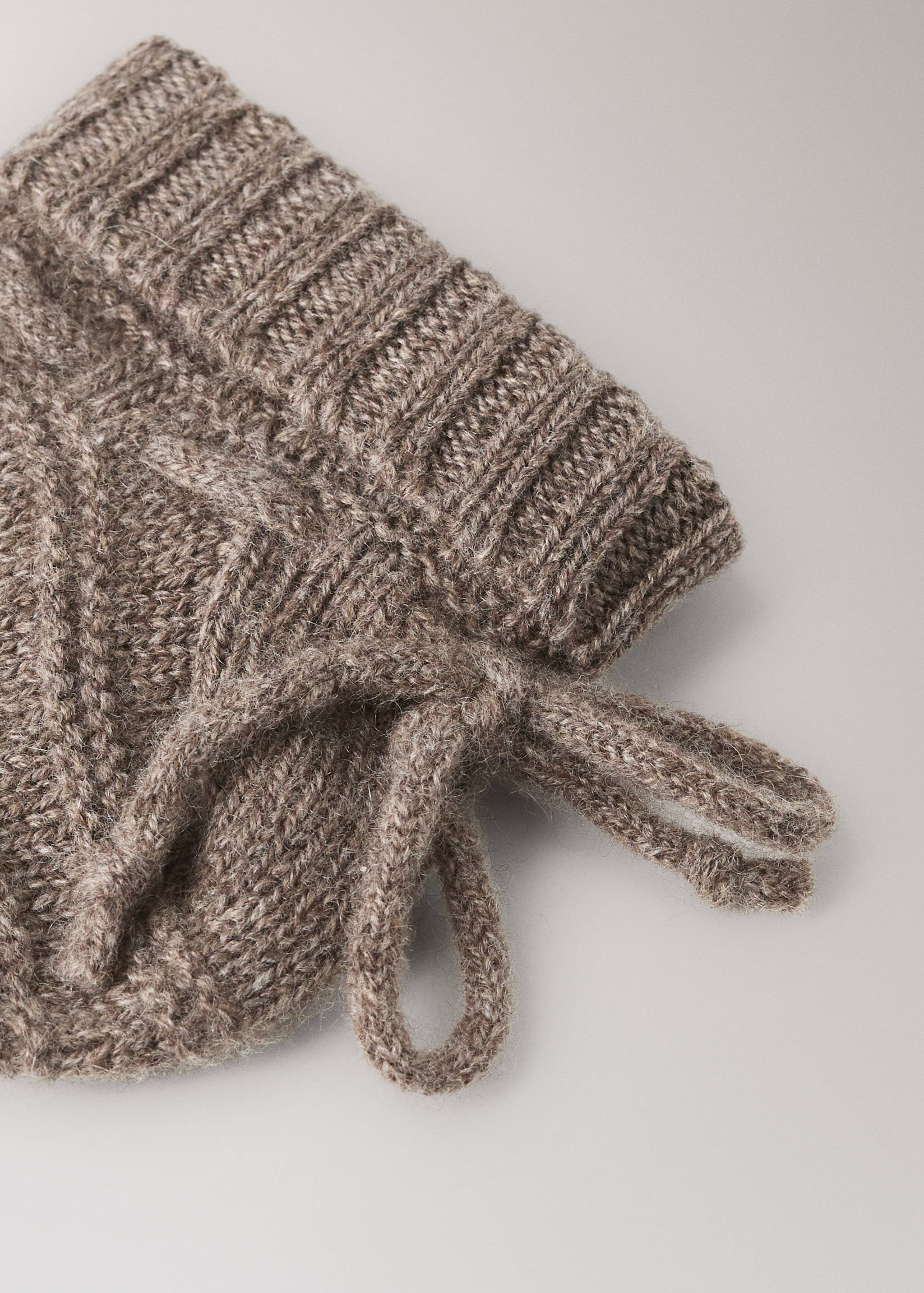 Brown cable-knit socks detail featuring a ribbed cuff and ties.