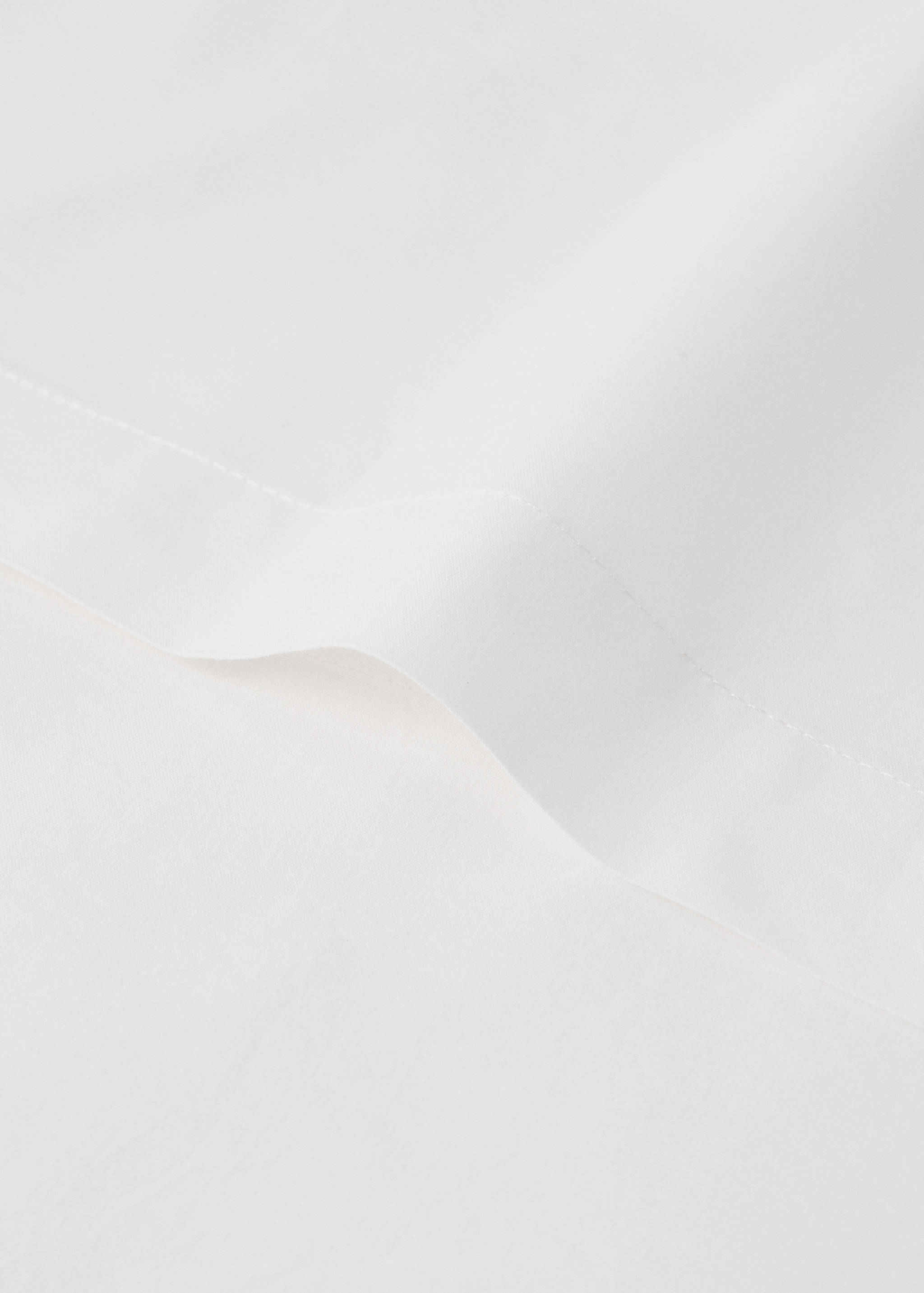 Close-up of the smooth texture and stitched border of a white duvet cover.