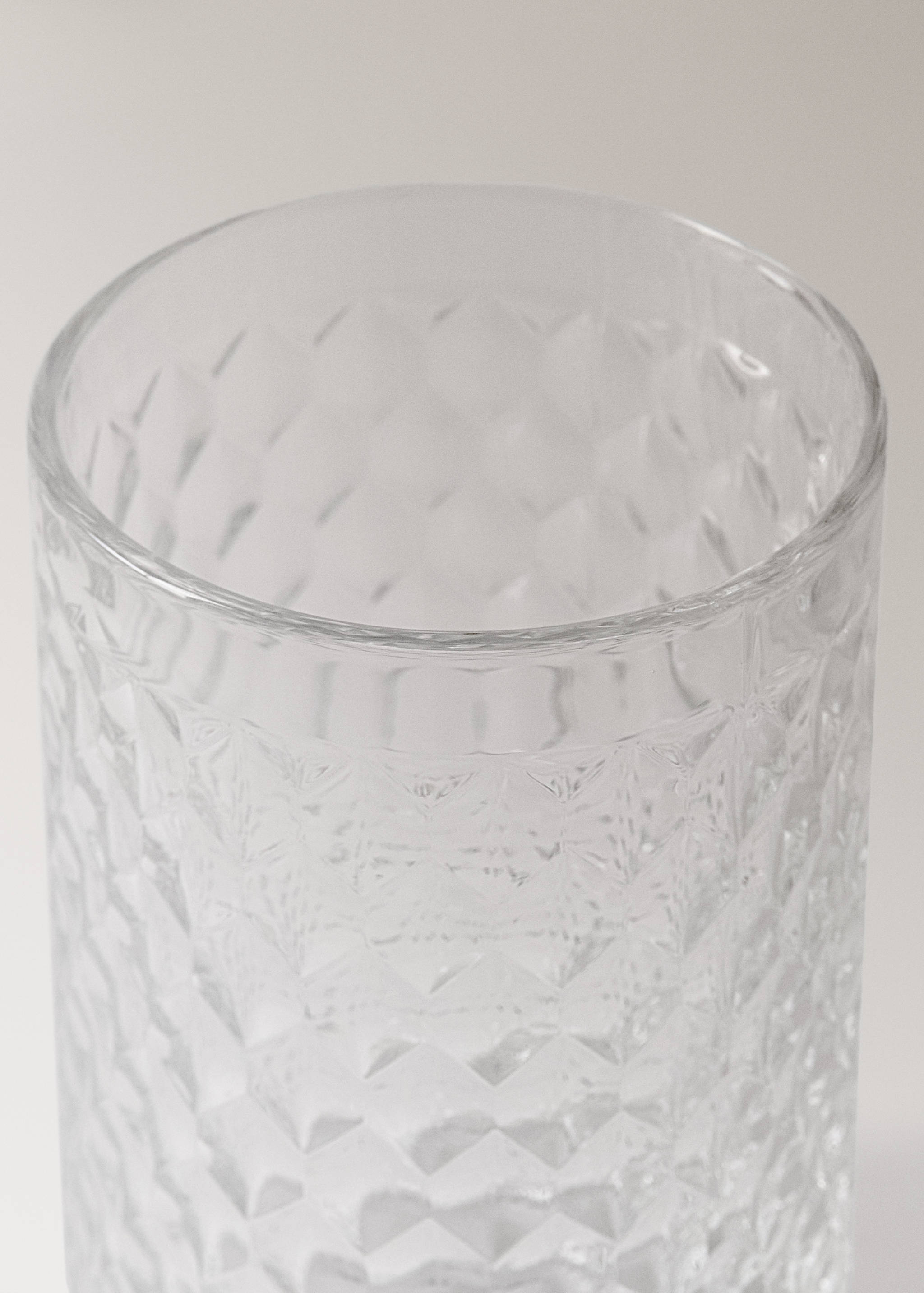Clear glass tumbler with a textured geometric pattern.