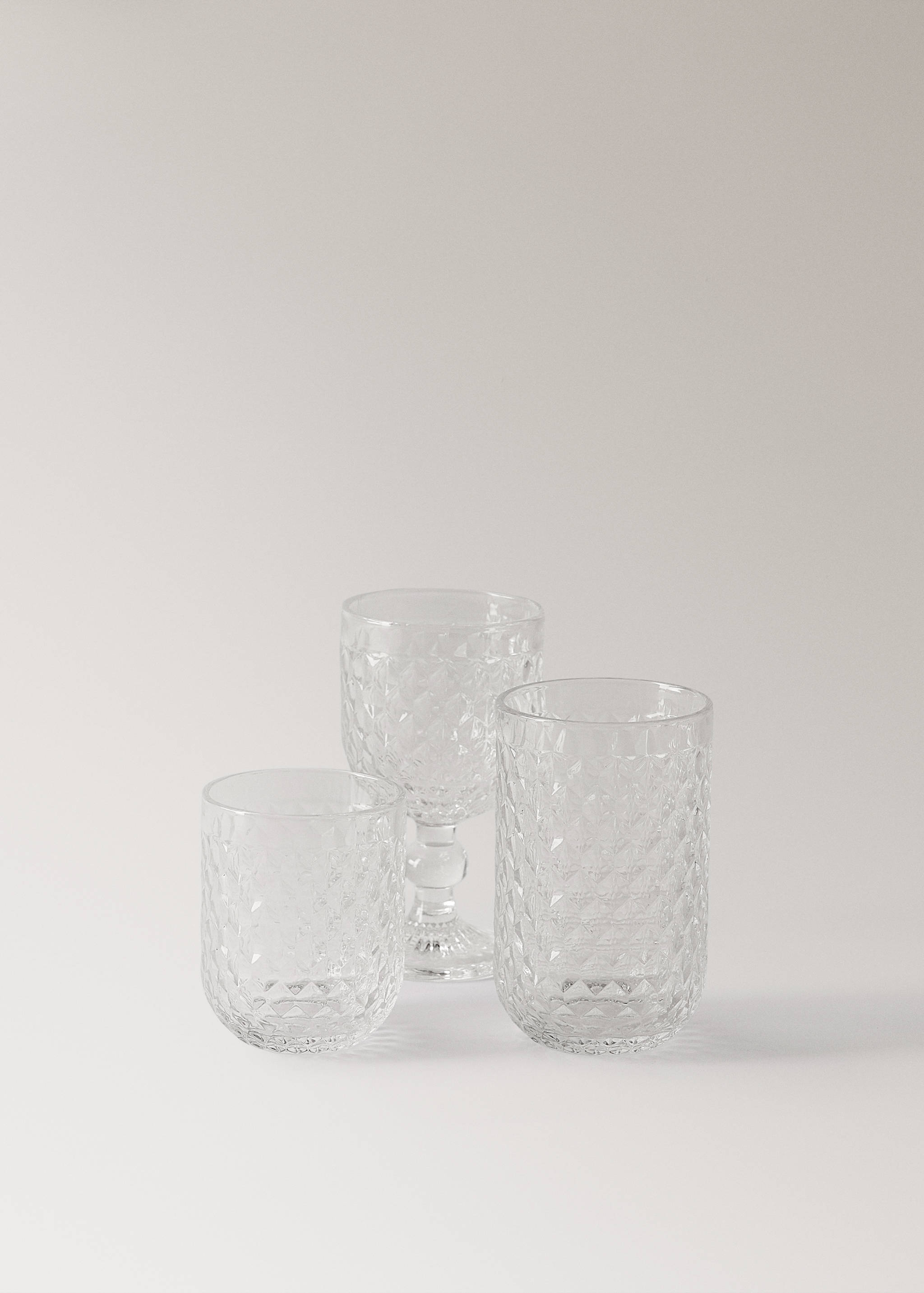 Set of three clear glass tumblers and a wine glass featuring a faceted diamond-cut pattern.