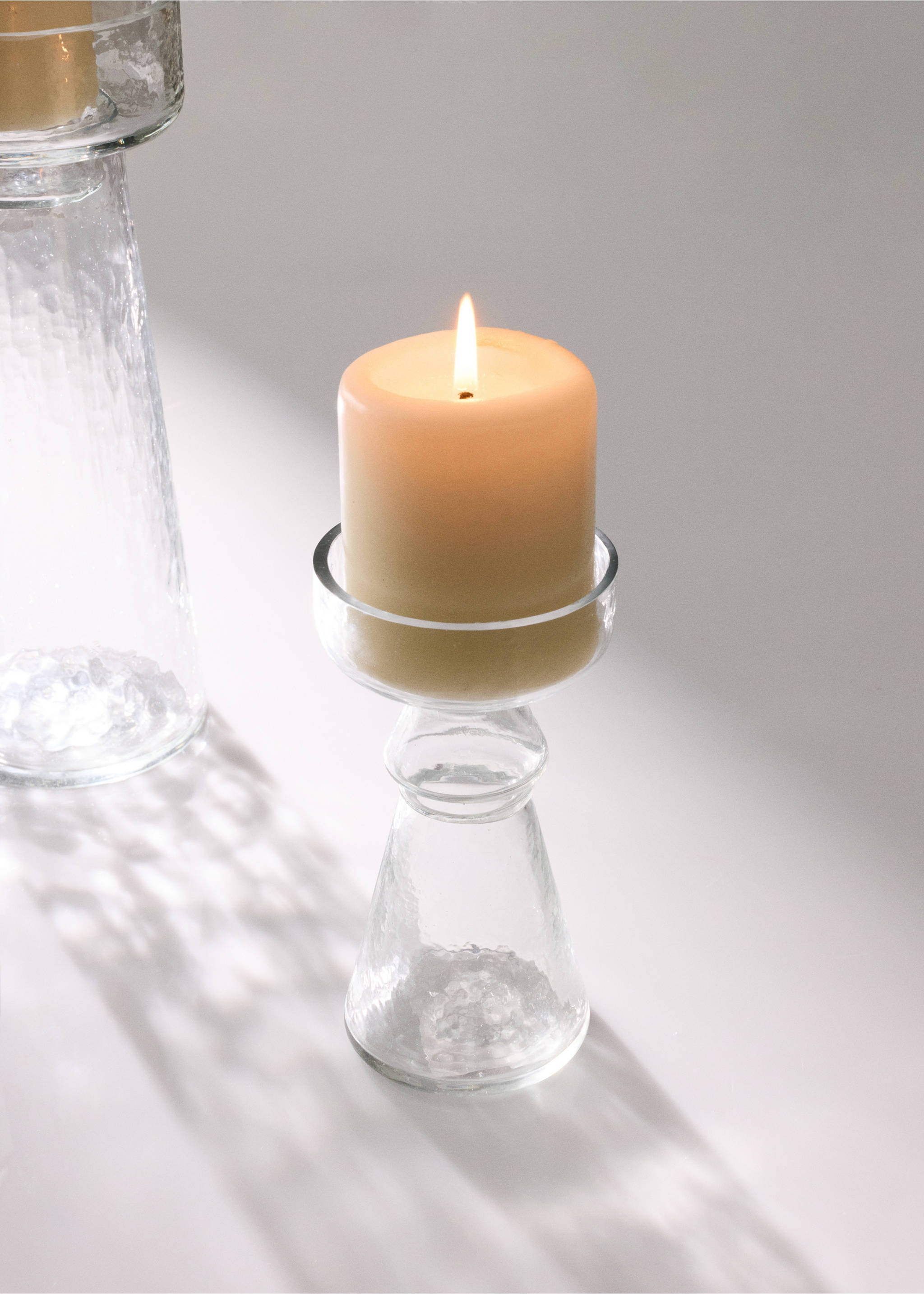 Clear glass candleholder with a lit cream pillar candle., Black. Ref: 37063293-00.
