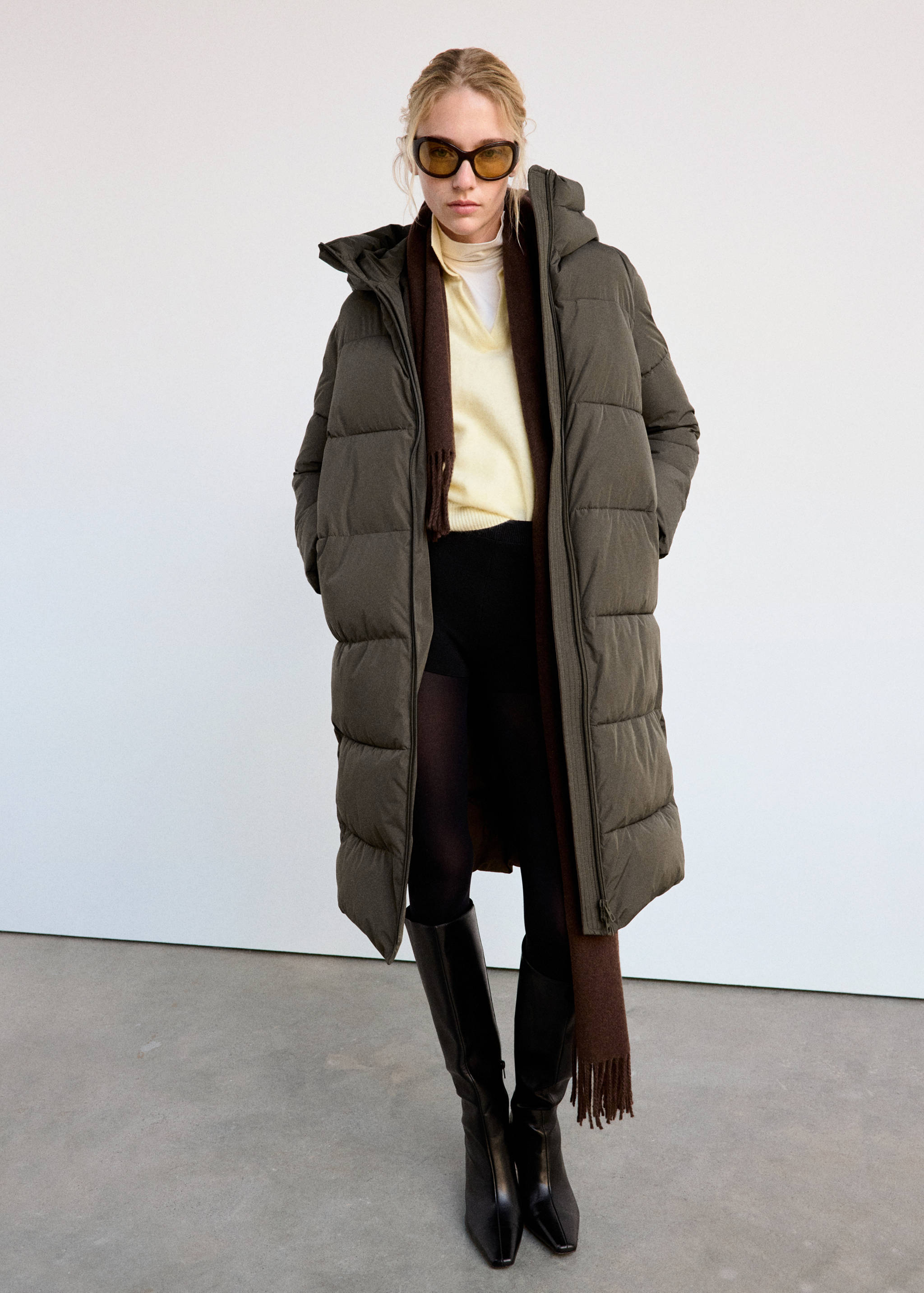 Long quilted dark green anorak with a hood.