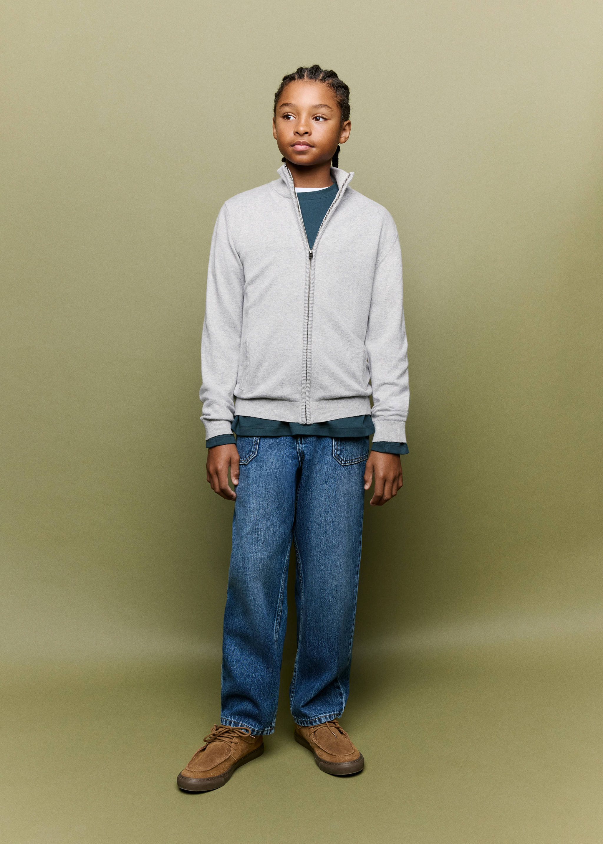 Grey zip-up cardigan with a high collar and ribbed trims, worn over a dark t-shirt and blue denim trousers.