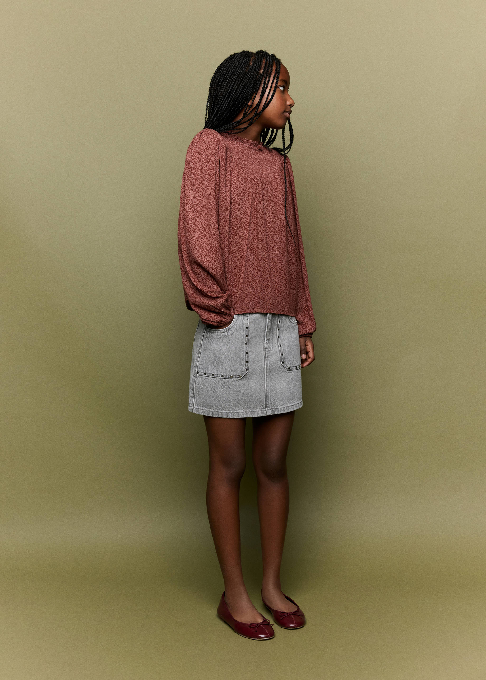 Grey denim mini skirt with front patch pockets and stud detailing, styled with a patterned blouse.