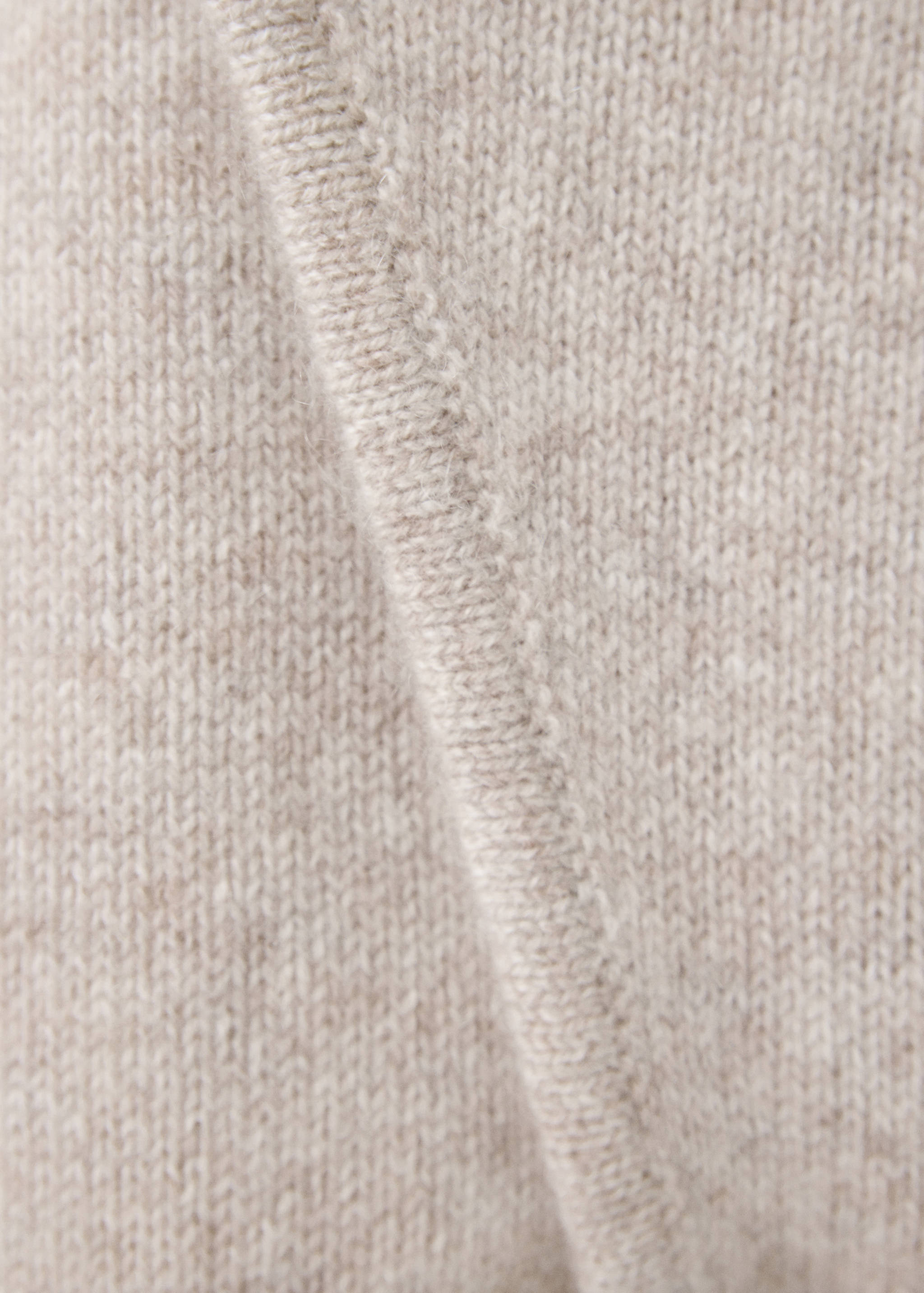 Close-up of the beige knit fabric and trim on a kids jumpsuit.