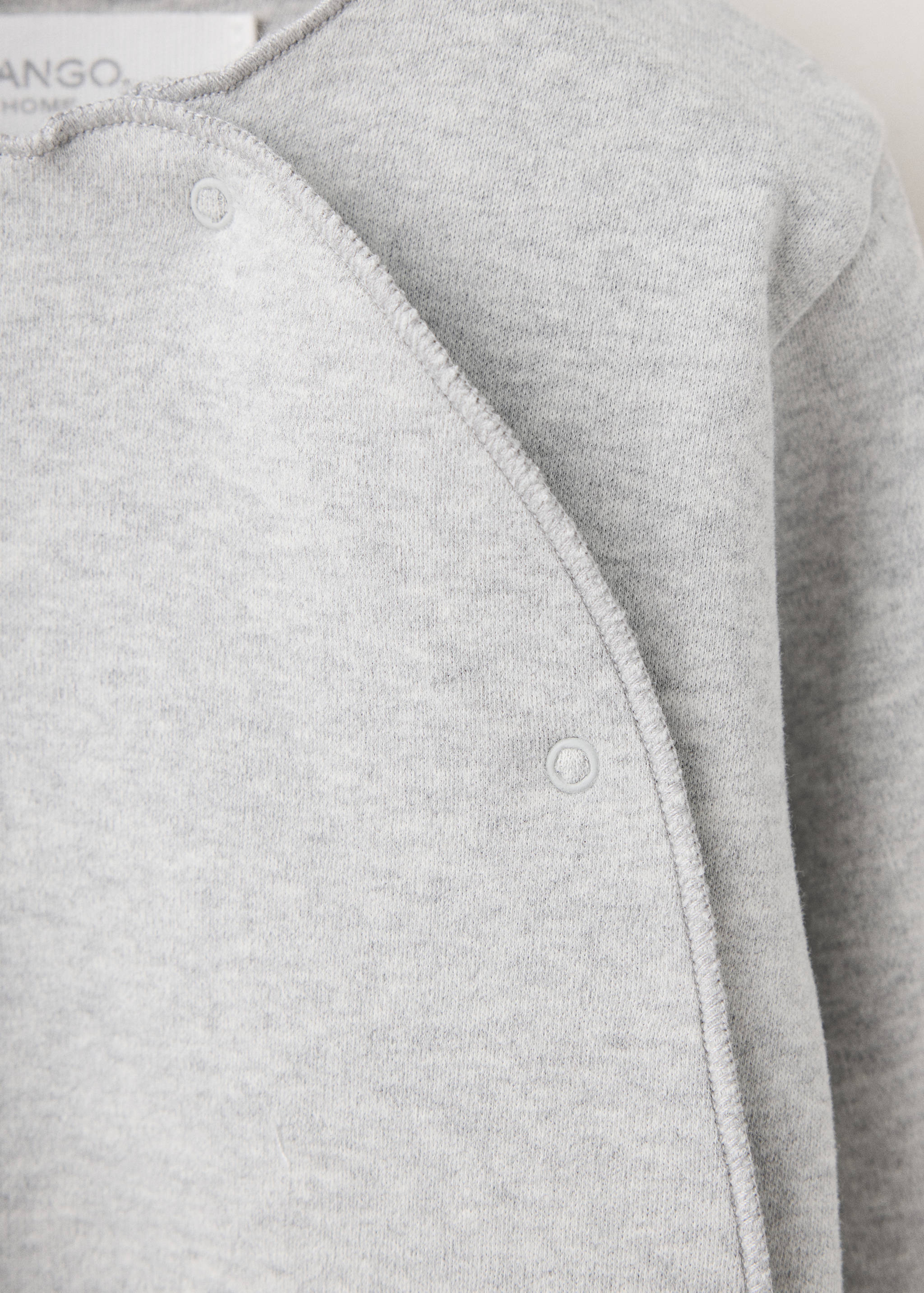 Close-up of a grey marl baby onesie with crossover press-stud fastening.