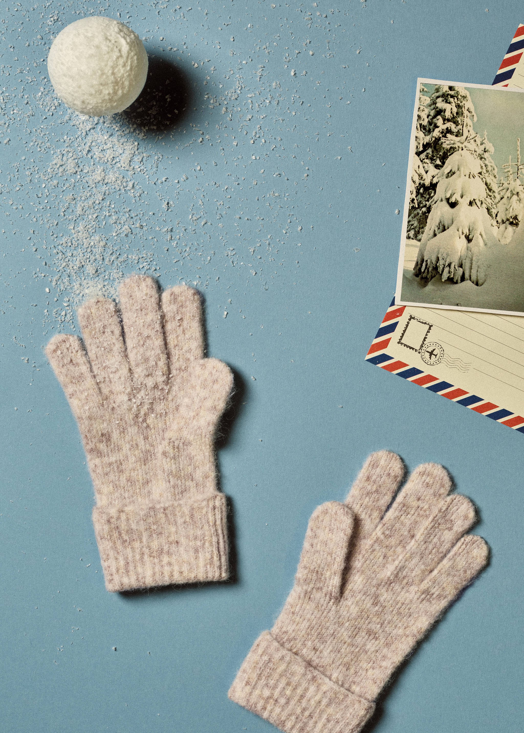 Beige melange knit gloves with ribbed cuffs on a blue background.