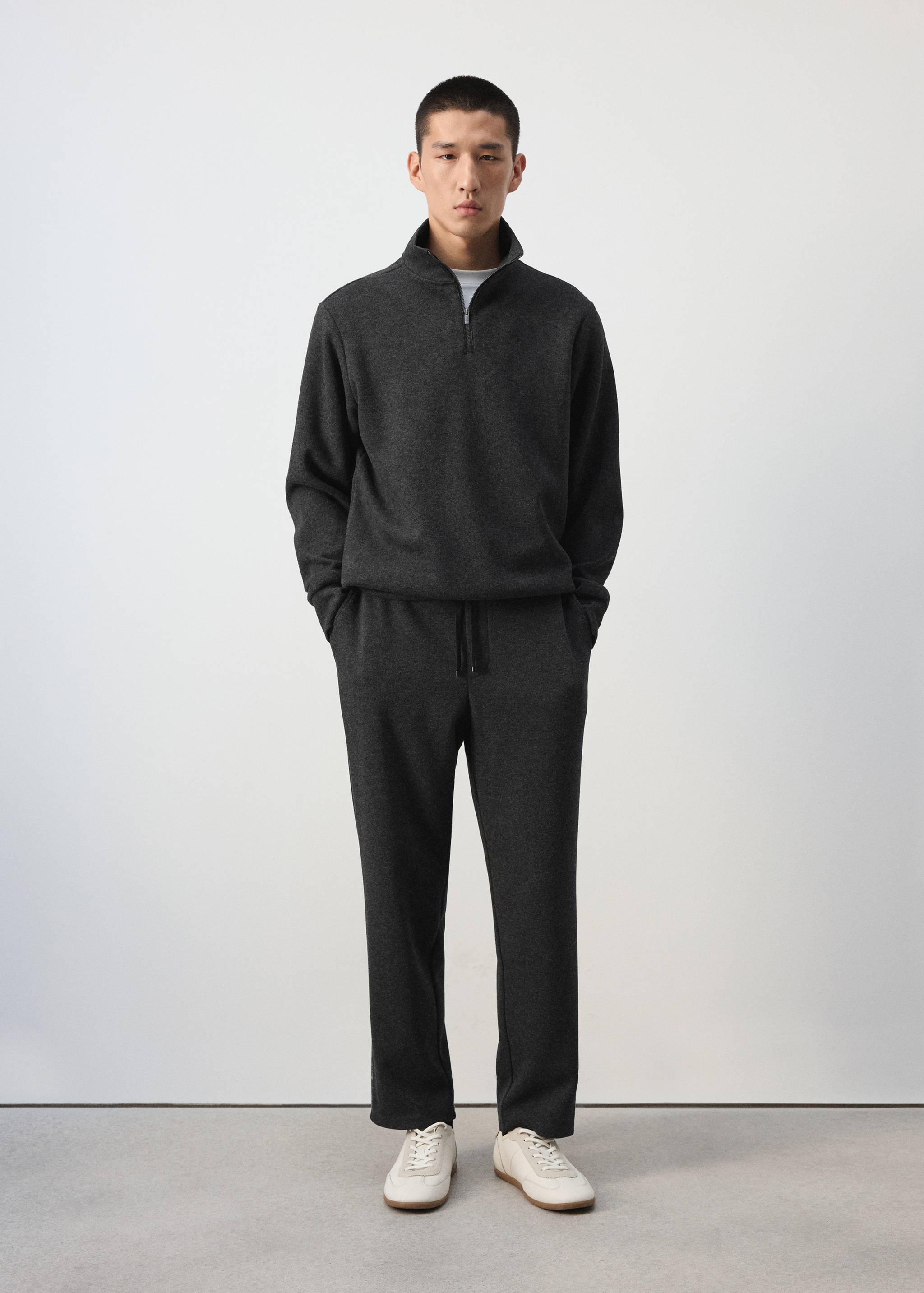 Charcoal grey joggers with a drawstring waist, worn with a matching quarter-zip sweatshirt.