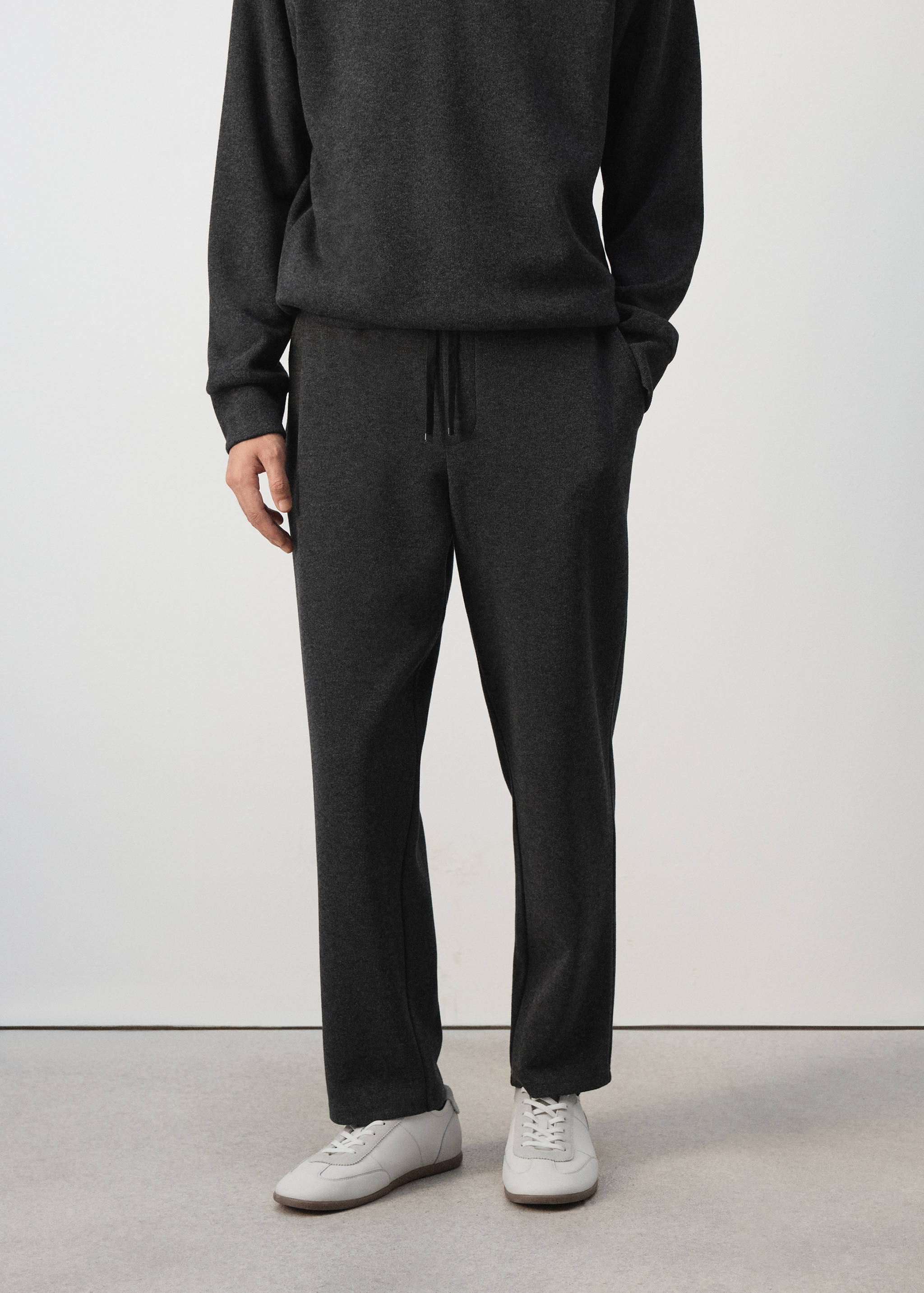 Dark grey joggers with an elasticated drawstring waistband, worn with a matching sweatshirt.