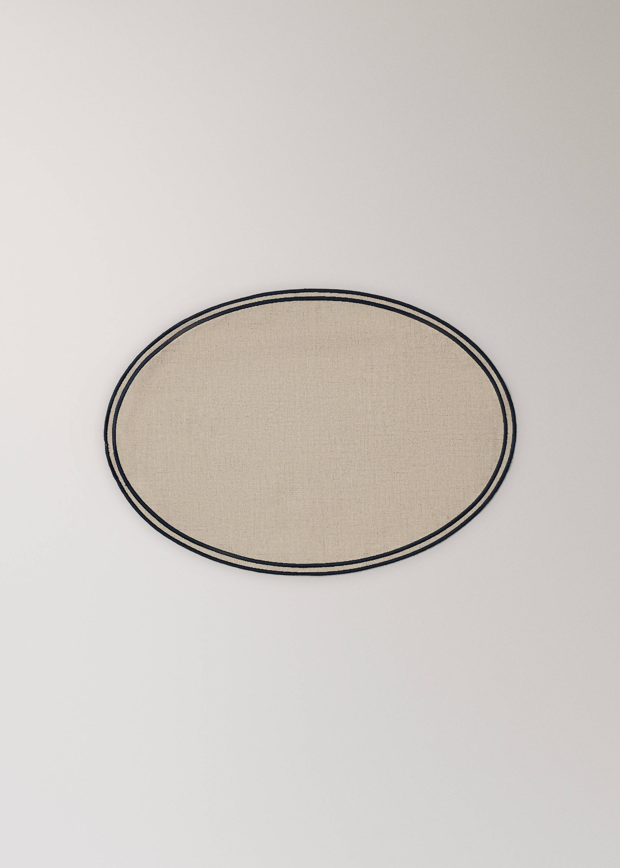 Beige oval placemat with a double navy blue border.