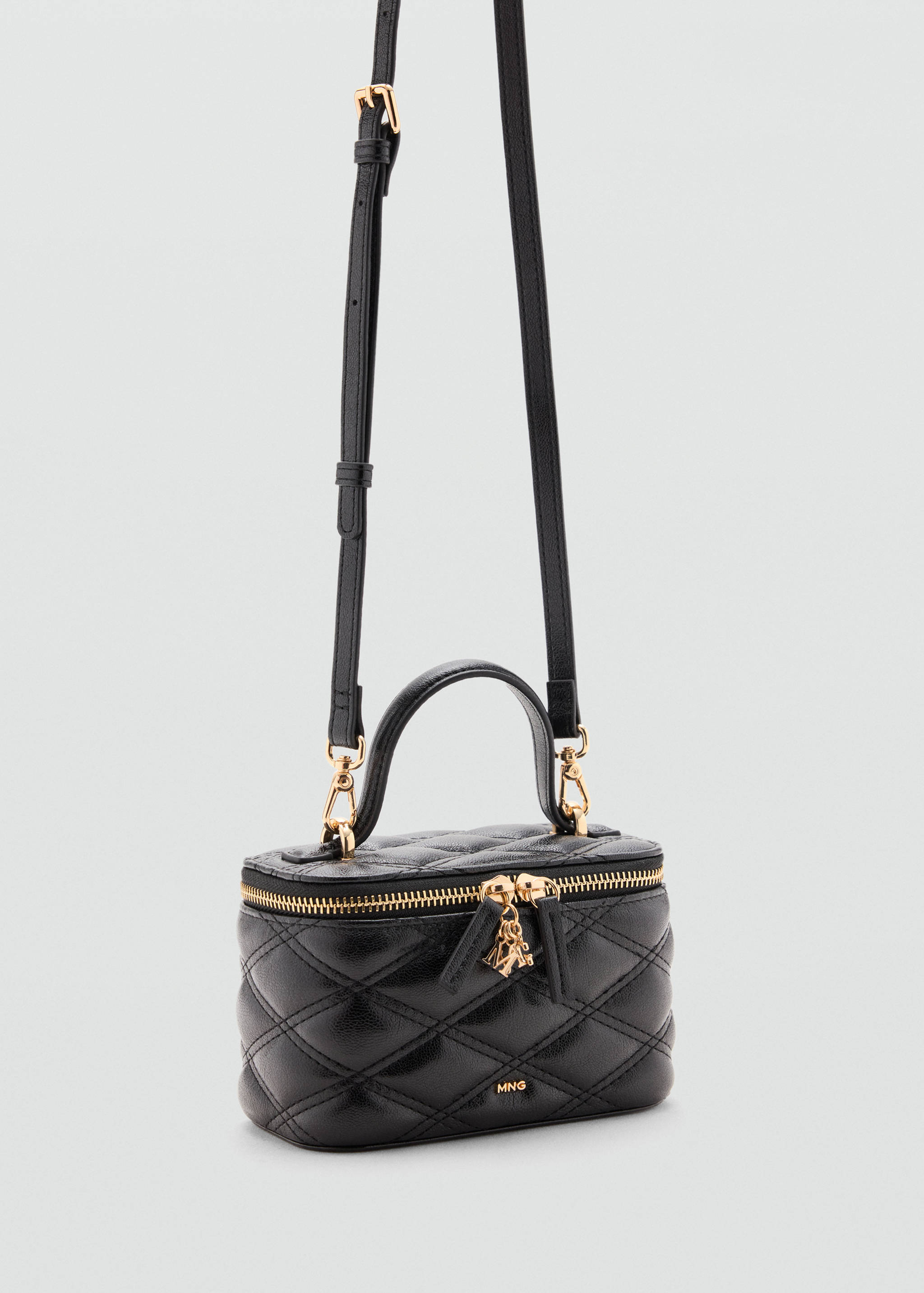 Black quilted vanity bag with a top handle, gold-toned hardware, and a shoulder strap.