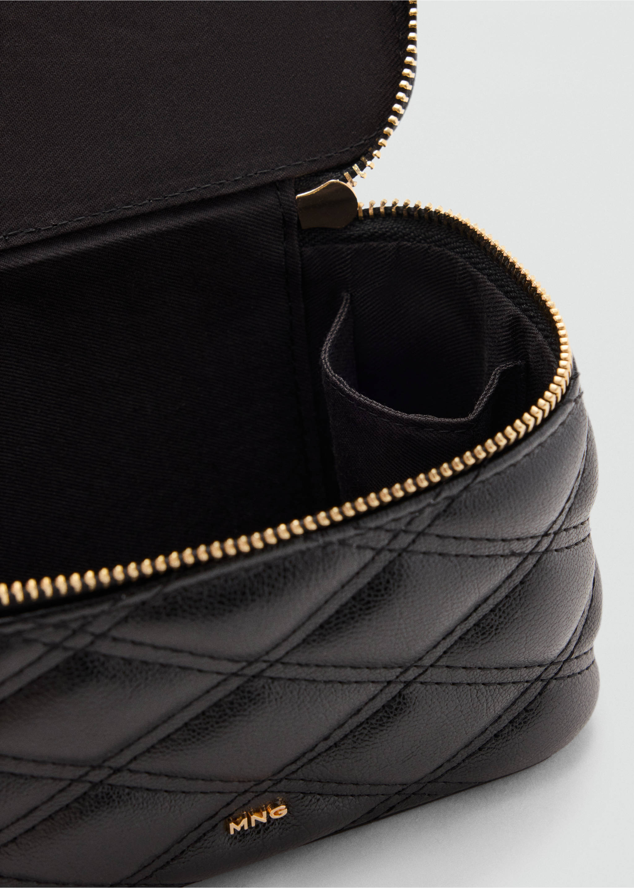 Close-up of a black quilted vanity case interior and gold zip., Black. Ref: 37066365-00.