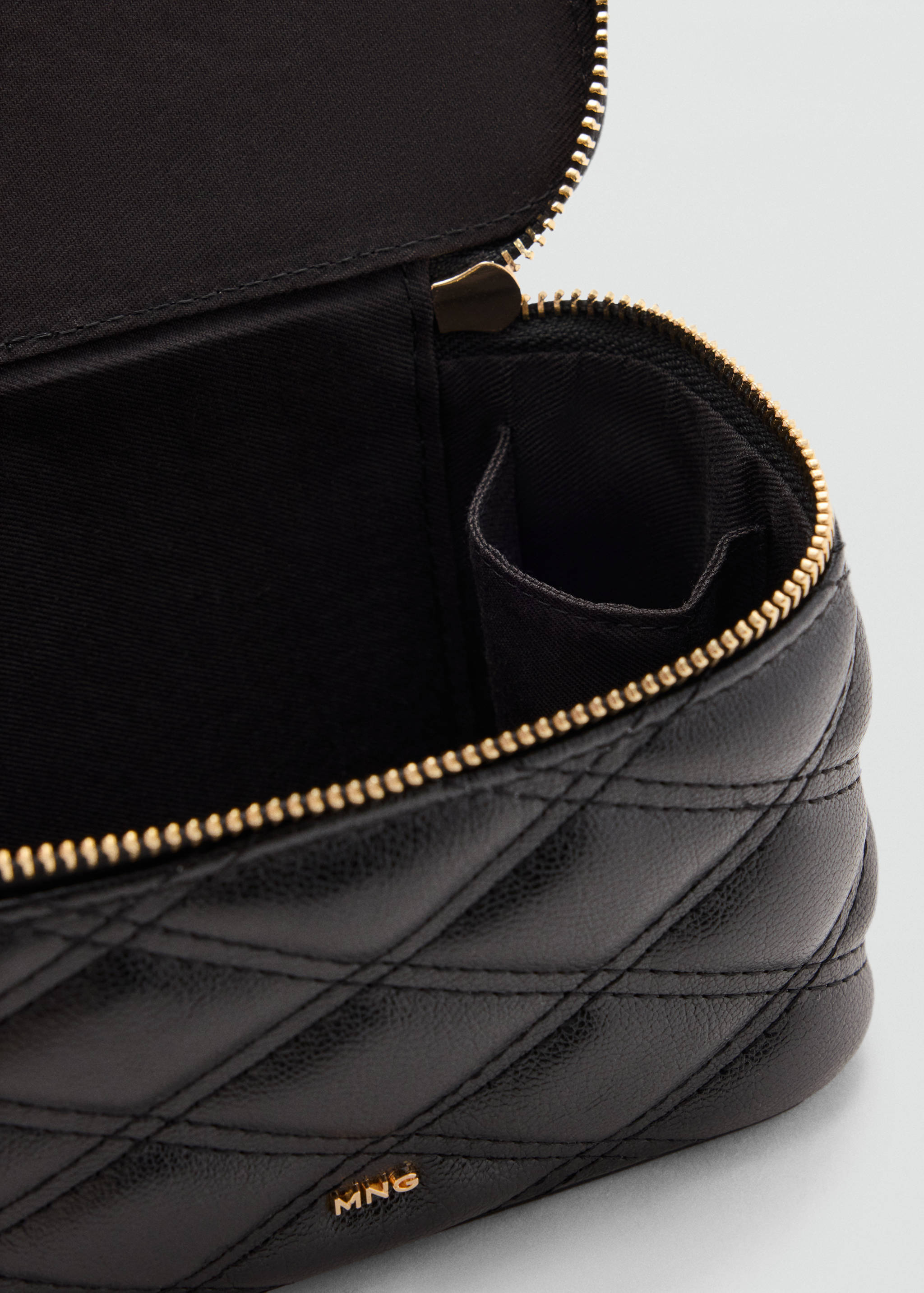 Close-up of a black quilted vanity case interior and gold zip.