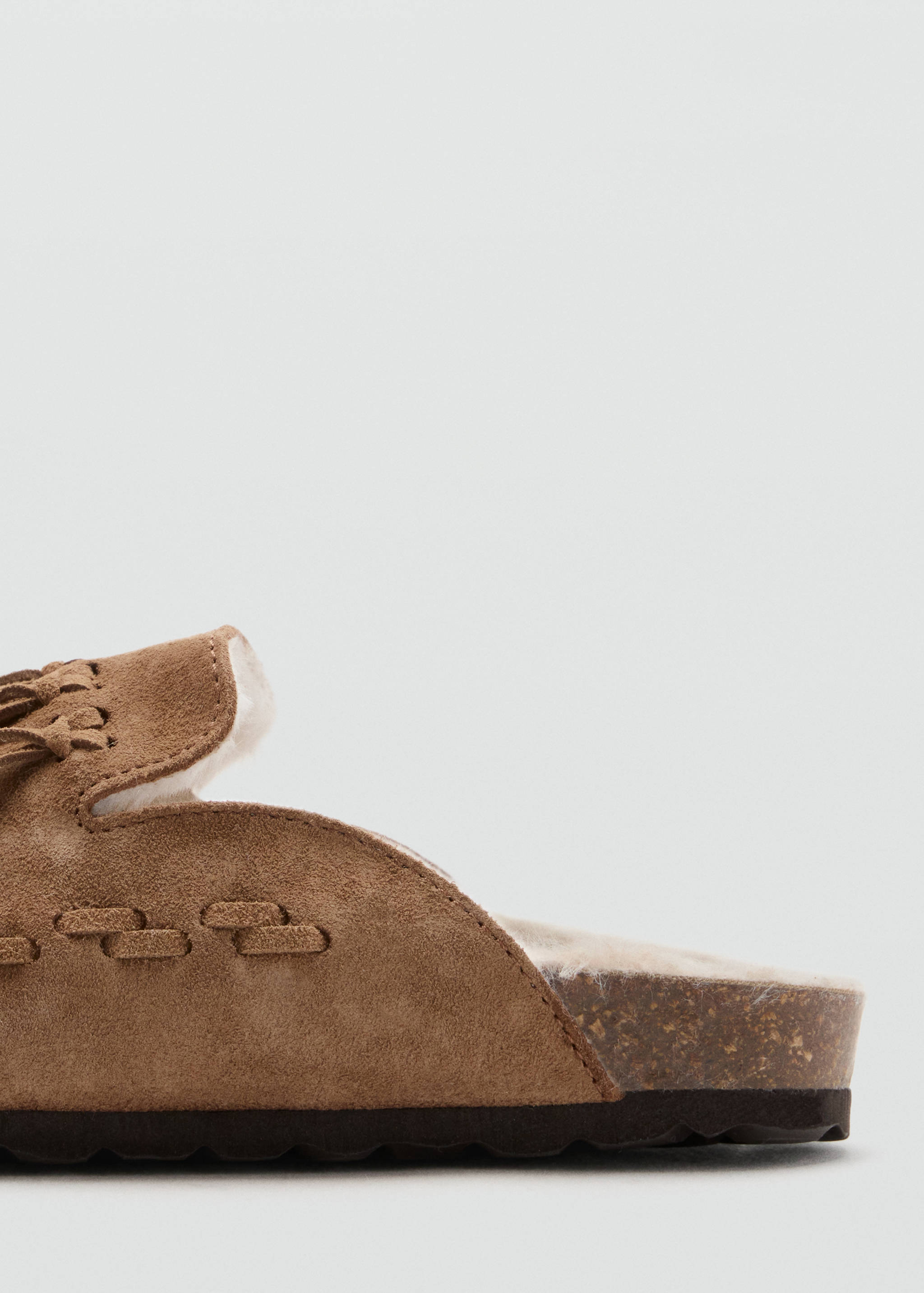 Brown suede shoe detail with white faux-fur lining and cork midsole.