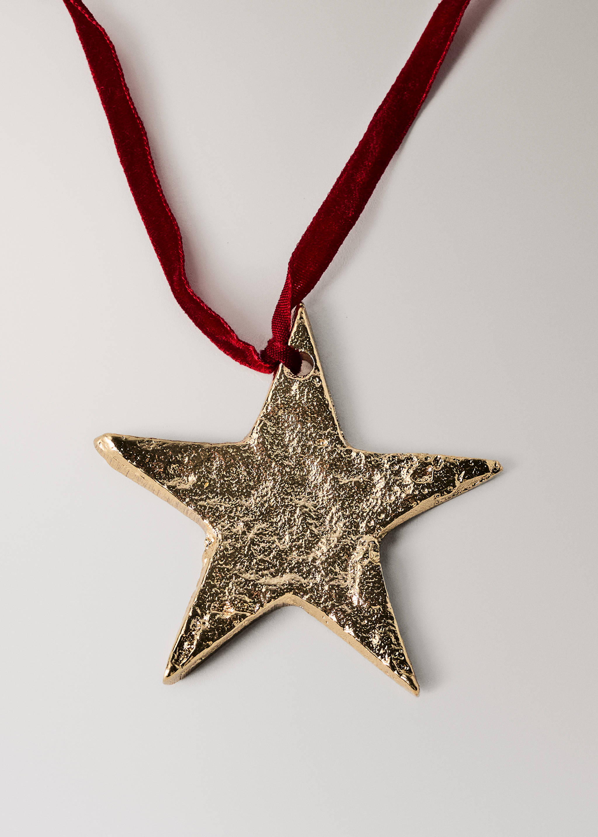 Textured gold star-shaped decoration with a red velvet ribbon.